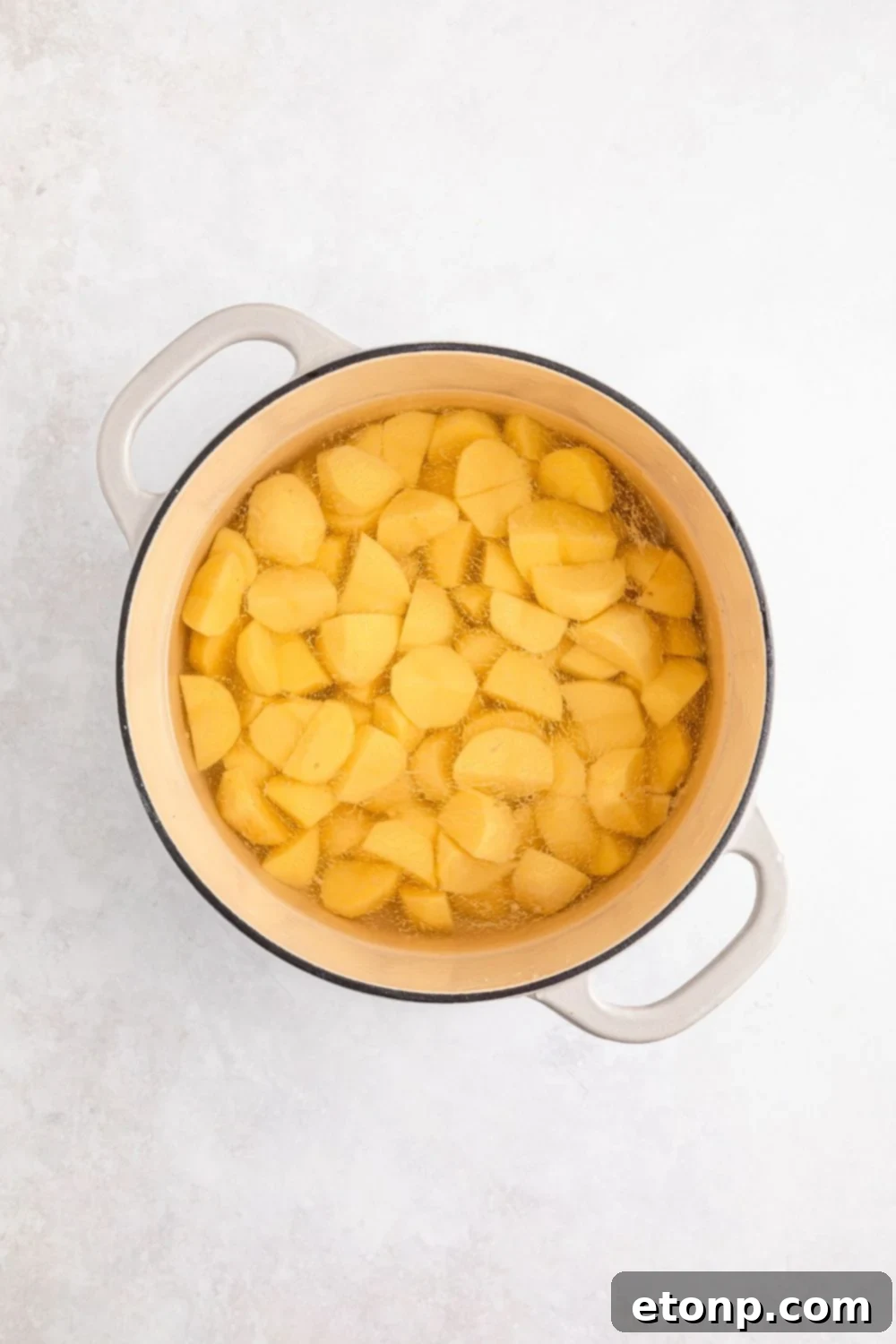 Peeled and diced potatoes in a pot with water sitting on a table, ready for boiling