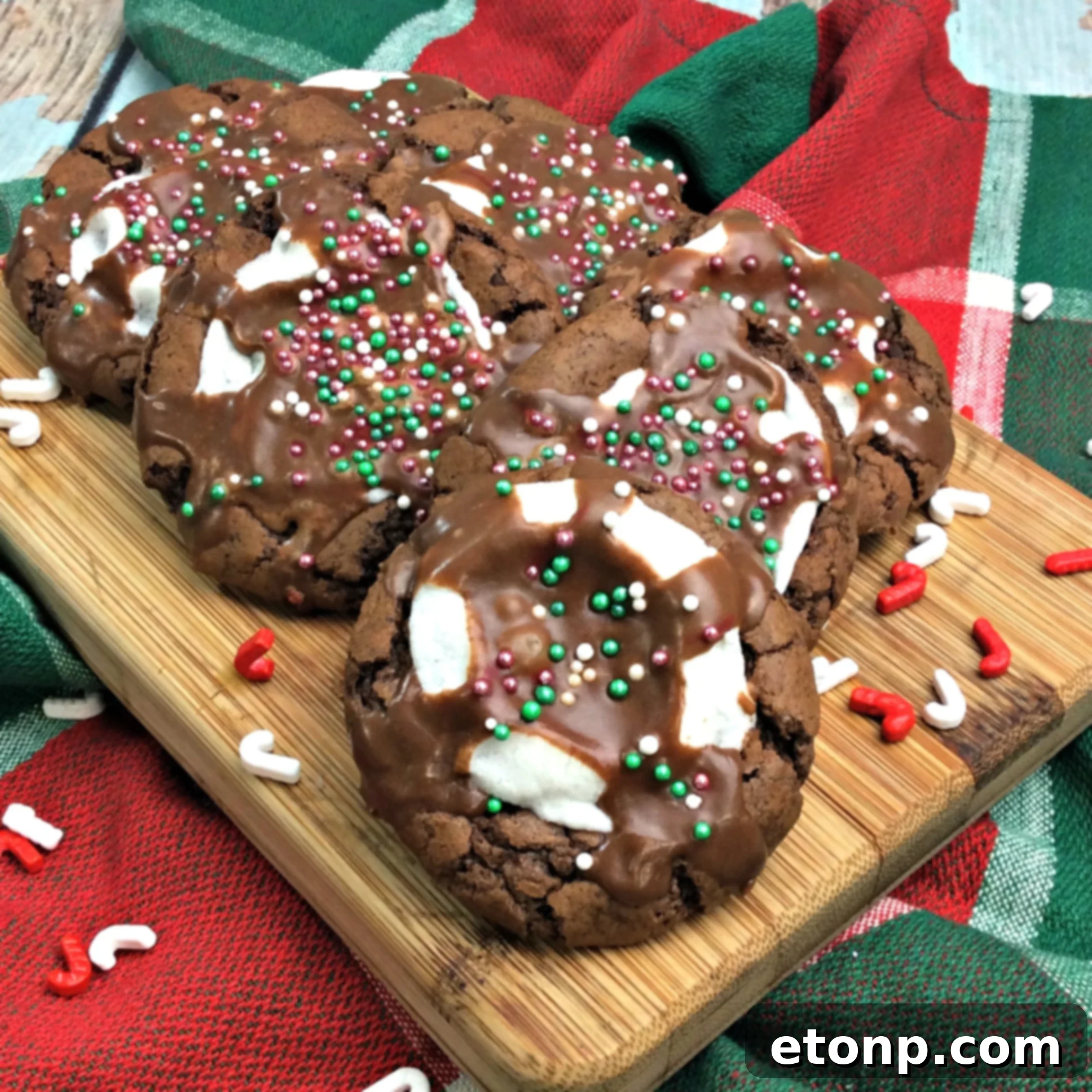 Three decadent hot cocoa marshmallow cookies on a cooling rack, showcasing their rich color and the inviting melt of the marshmallows before the final icing.