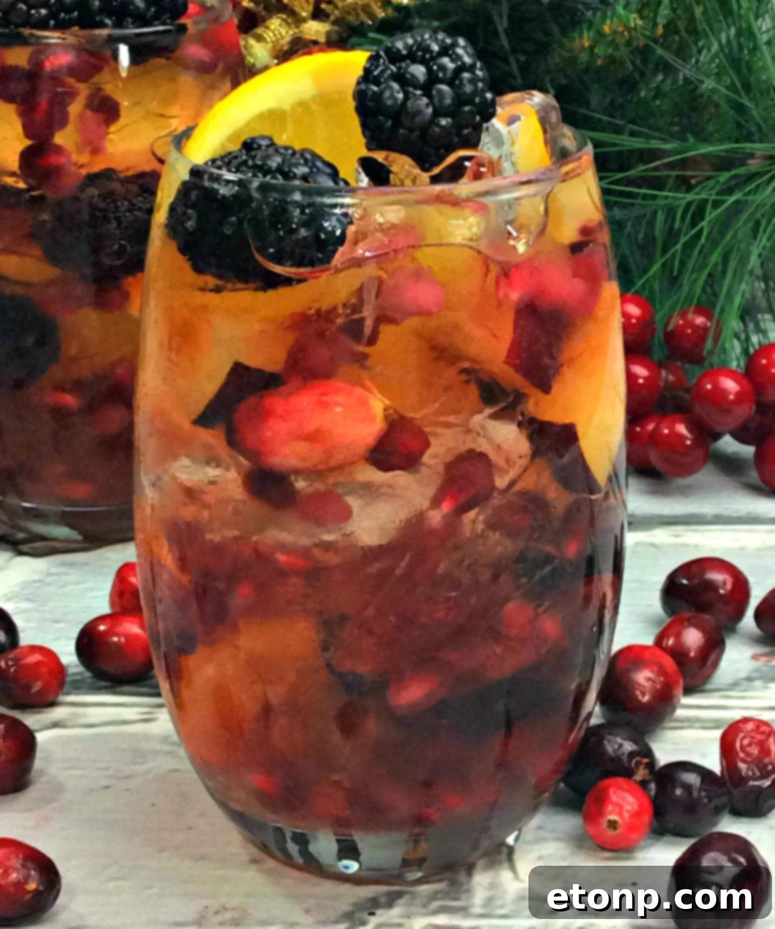 A vibrant pitcher of white wine sangria filled with blackberries, cranberries, pomegranate seeds, and orange slices, perfectly chilled and ready to be served at a festive gathering.