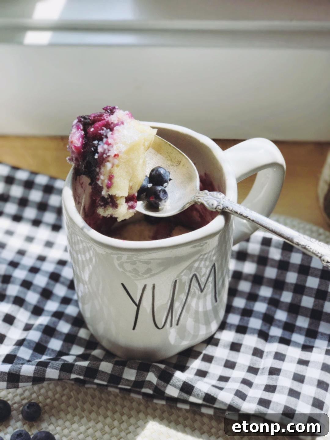 Blueberry muffin mug cake served with a spoon, showing its soft texture