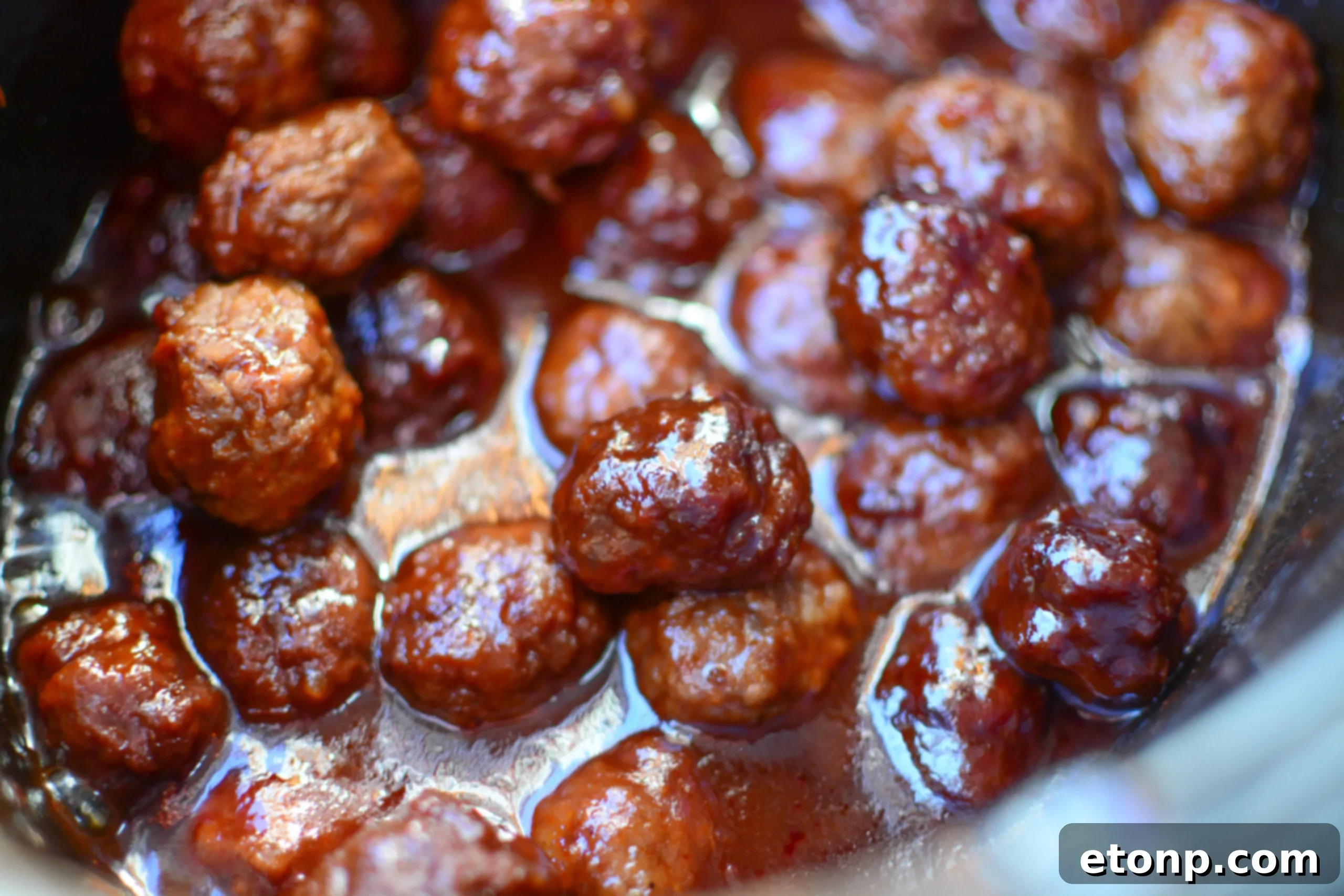 3 Malzemeli Tatlı Acı Yavaş Pişen Köfteler 4 Hand reaching for a sweet and spicy crock pot meatball with a toothpick, highlighting its easy-to-serve nature.
