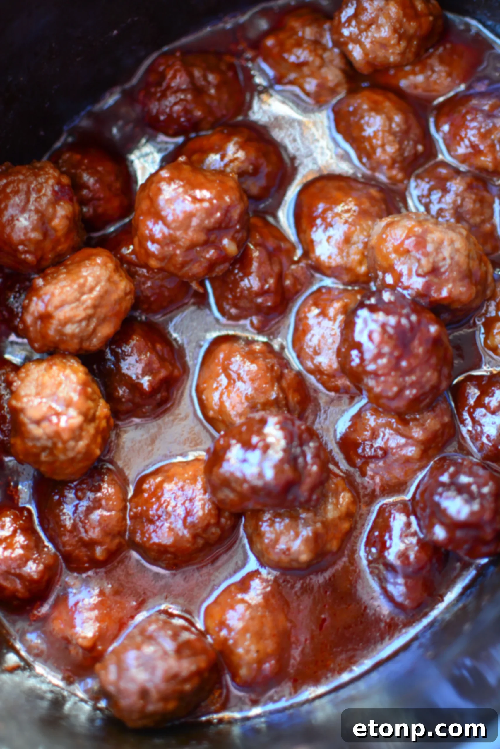 3 Malzemeli Tatlı Acı Yavaş Pişen Köfteler 6 A close-up shot of the glistening sweet and spicy glaze covering the cooked meatballs in a slow cooker.
