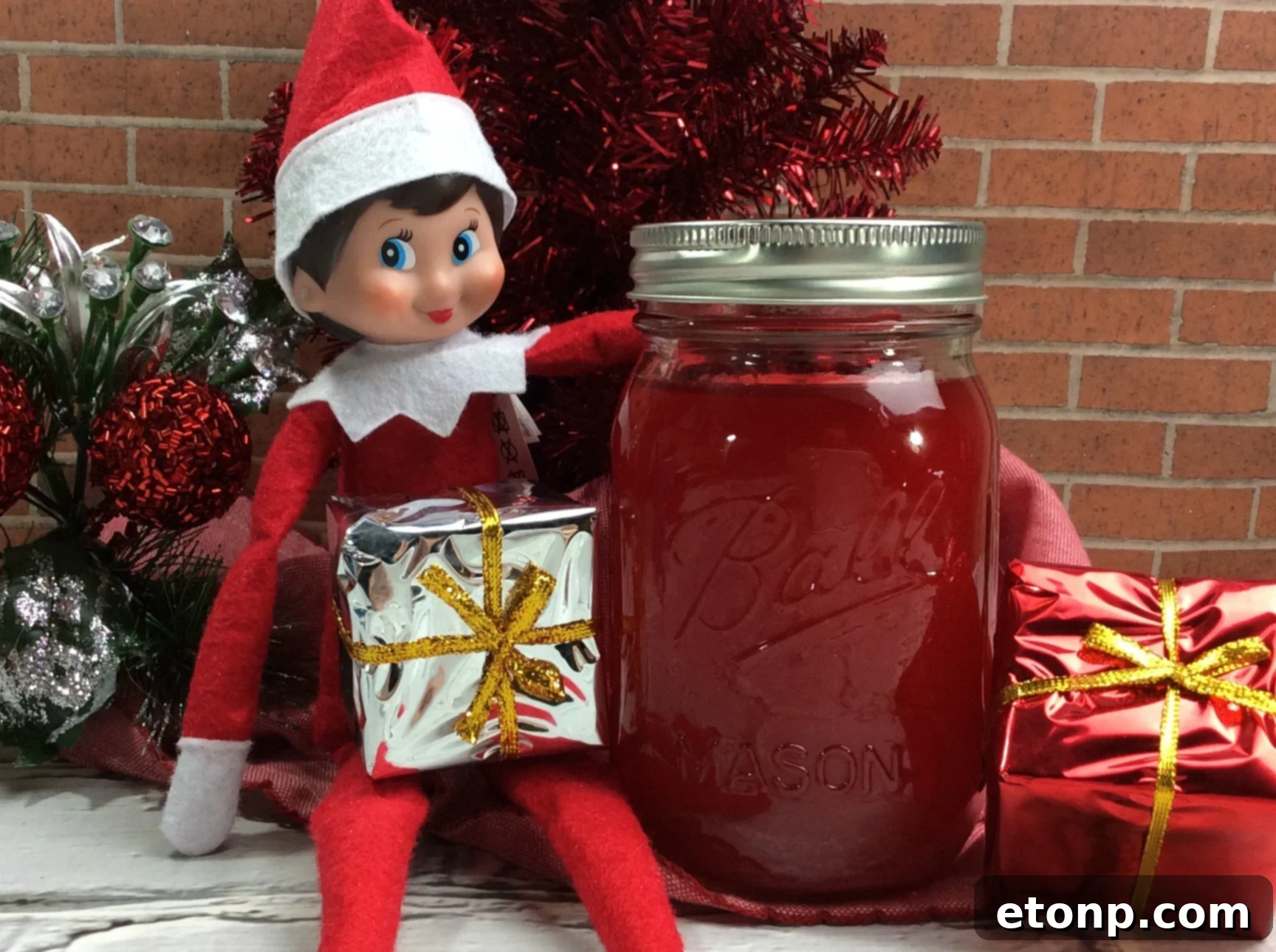 A festive glass of Elf Jungle Juice garnished with fresh kiwi, strawberries, and limes, set against a twinkling light background.