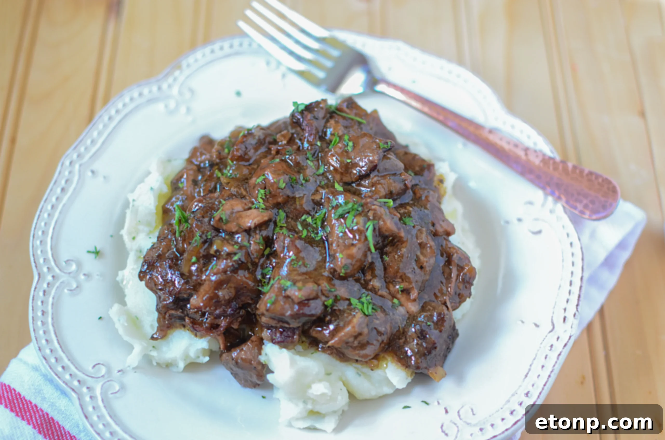 Serving slow cooker beef tips over creamy mashed potatoes