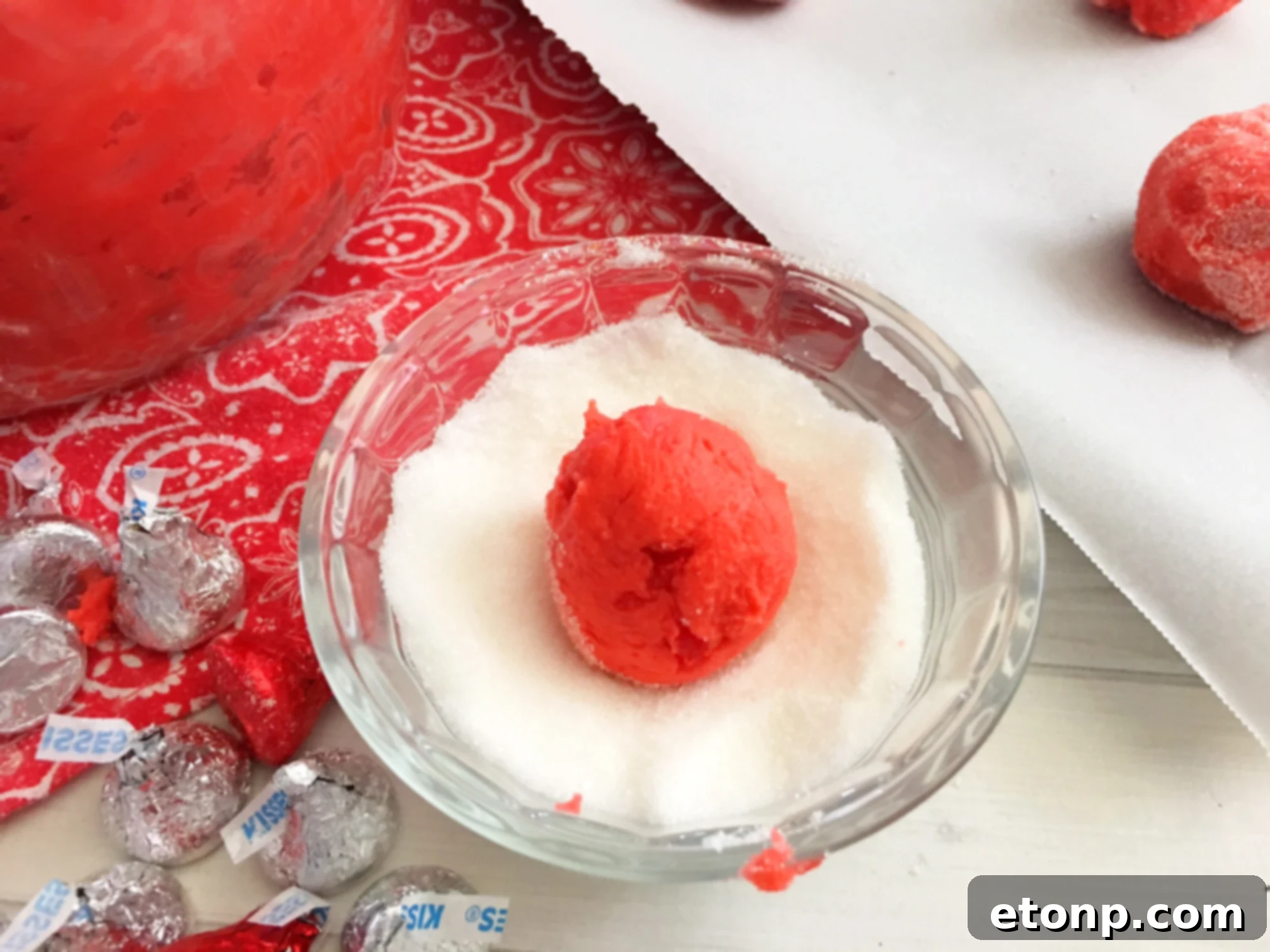 Close-up of a single Cherry Kiss Cookie, highlighting its soft, crinkled texture and the perfectly melted Hershey's Kiss.