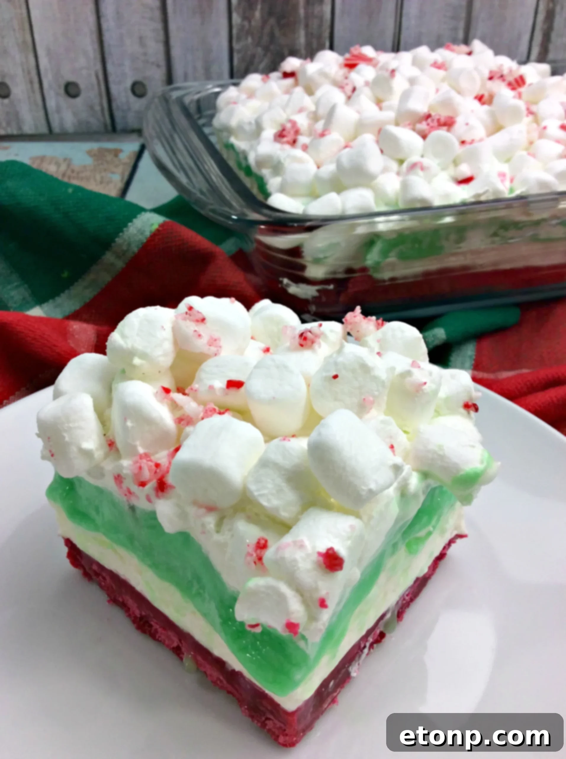 Overhead view of a full Christmas Cheesecake Lasagna in a baking dish, showcasing its vibrant layered structure and festive toppings, ready to be served.