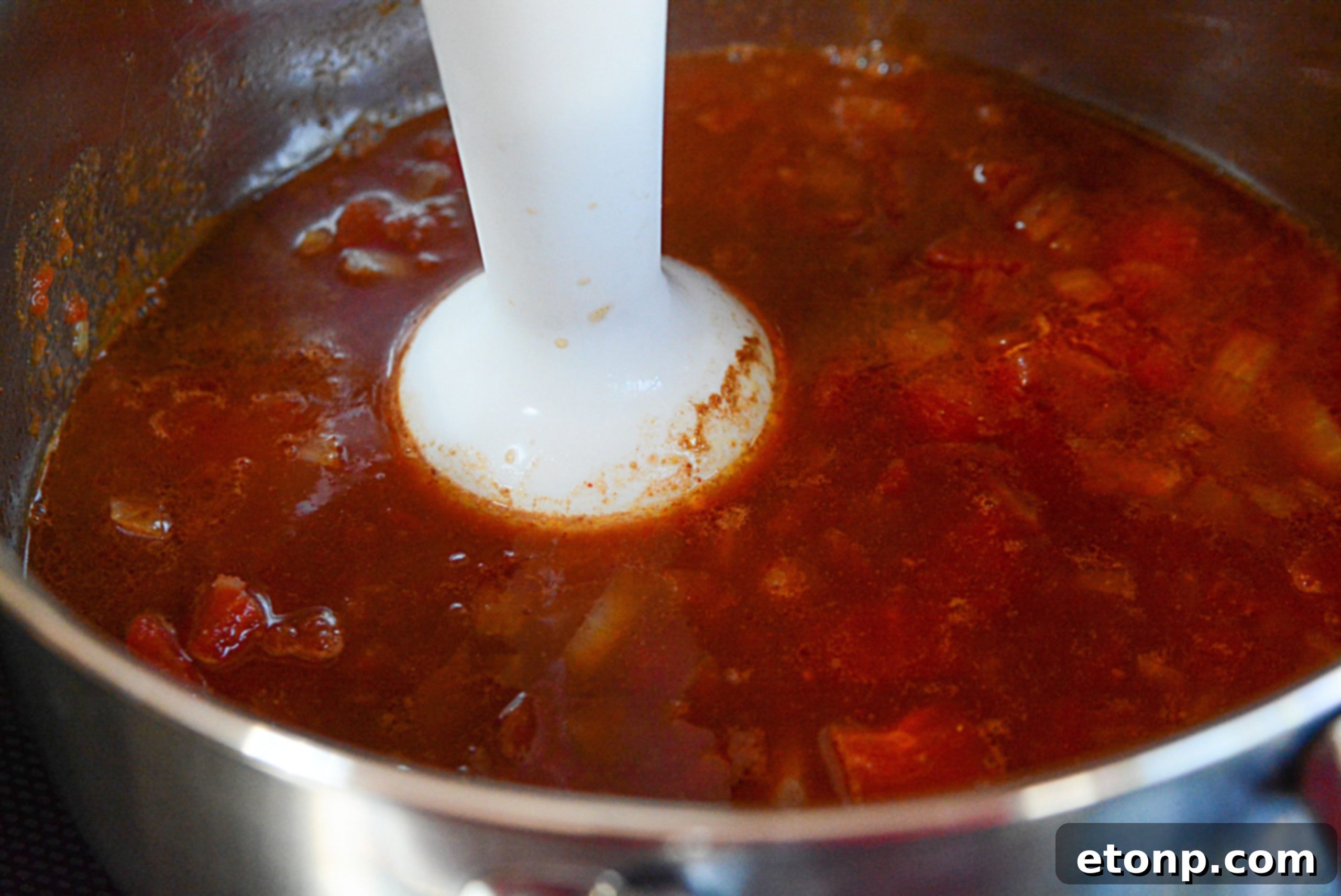 A vibrant display of fresh ingredients for crafting homemade root beer BBQ sauce, including a bottle of root beer, diced tomatoes, and onions.