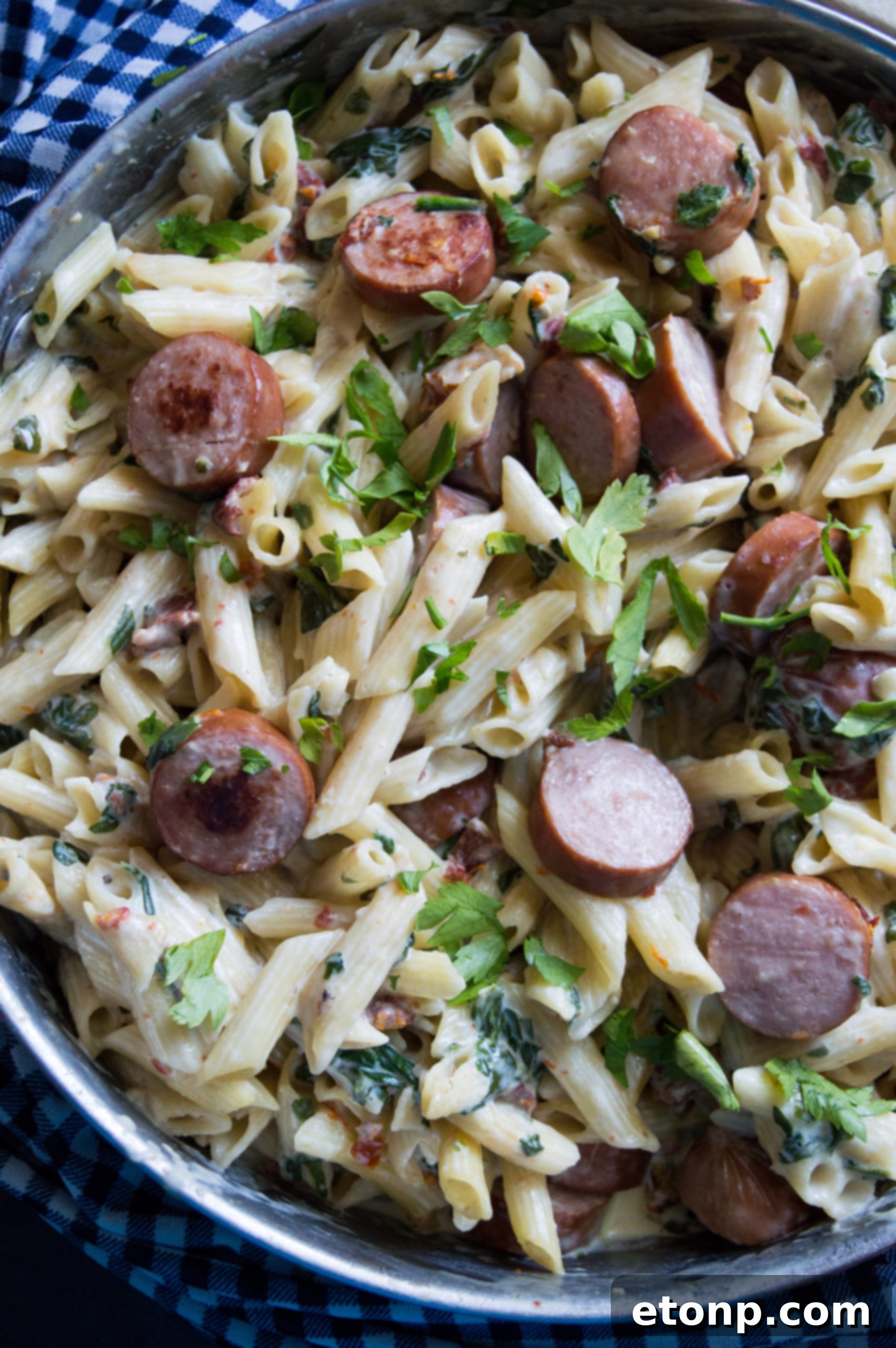 A spoonful of the creamy pasta dish being lifted from the pan, showing the rich sauce and ingredients.
