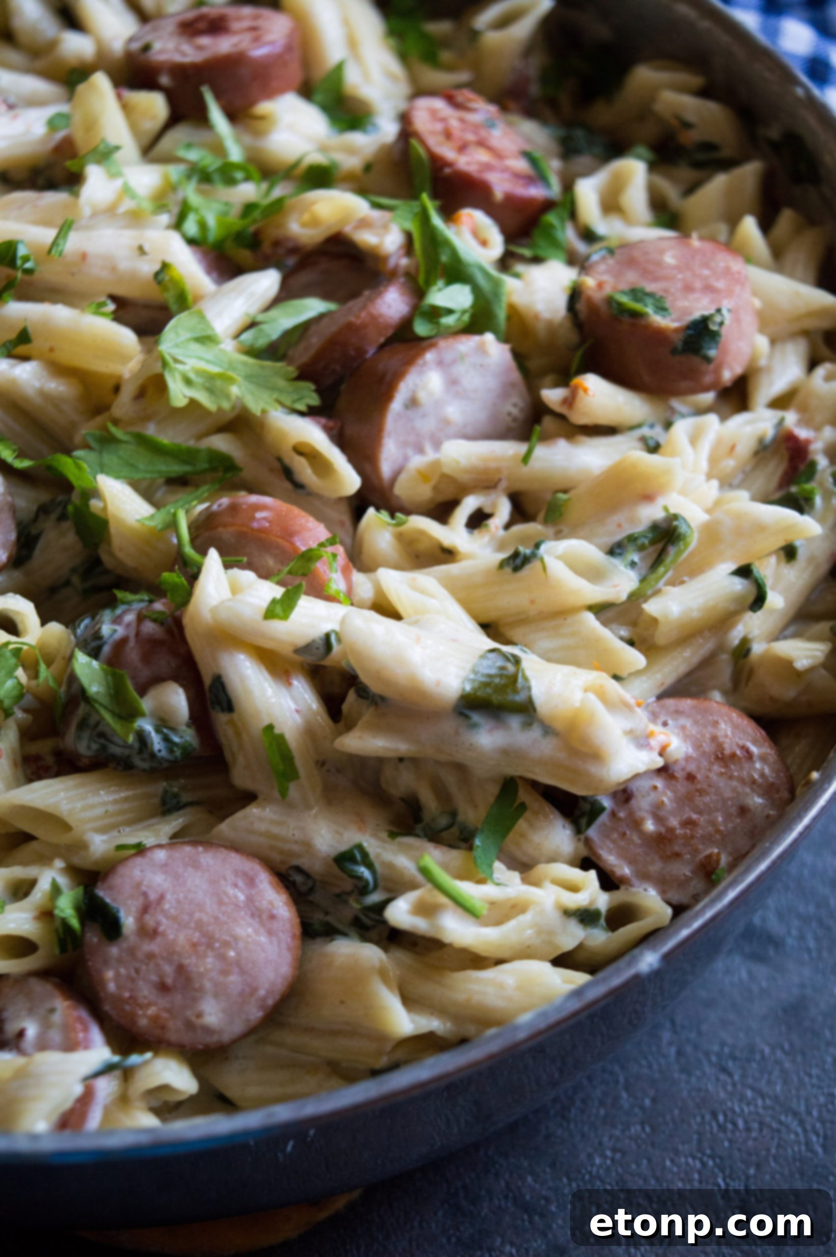 A beautifully plated portion of creamy pasta with spinach and sausage, ready to be served.