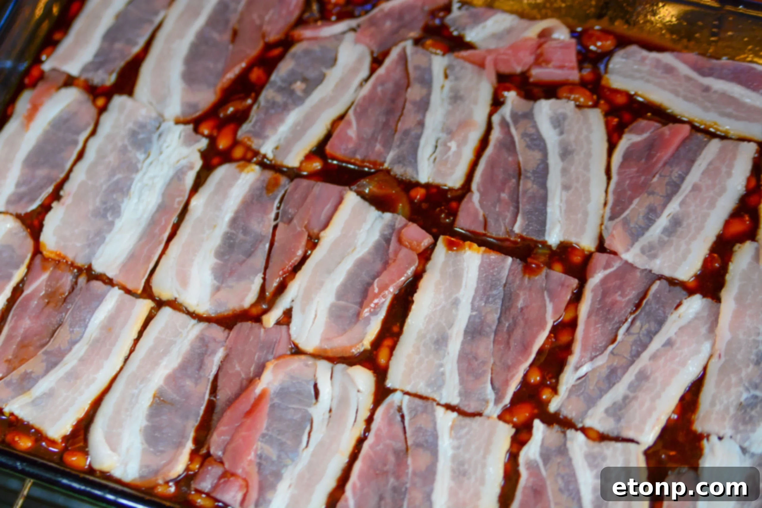 Ultimate Brown Sugar Bacon Baked Beans 4 Serving of brown sugar bacon baked beans with a fork, showing the crispy bacon topping