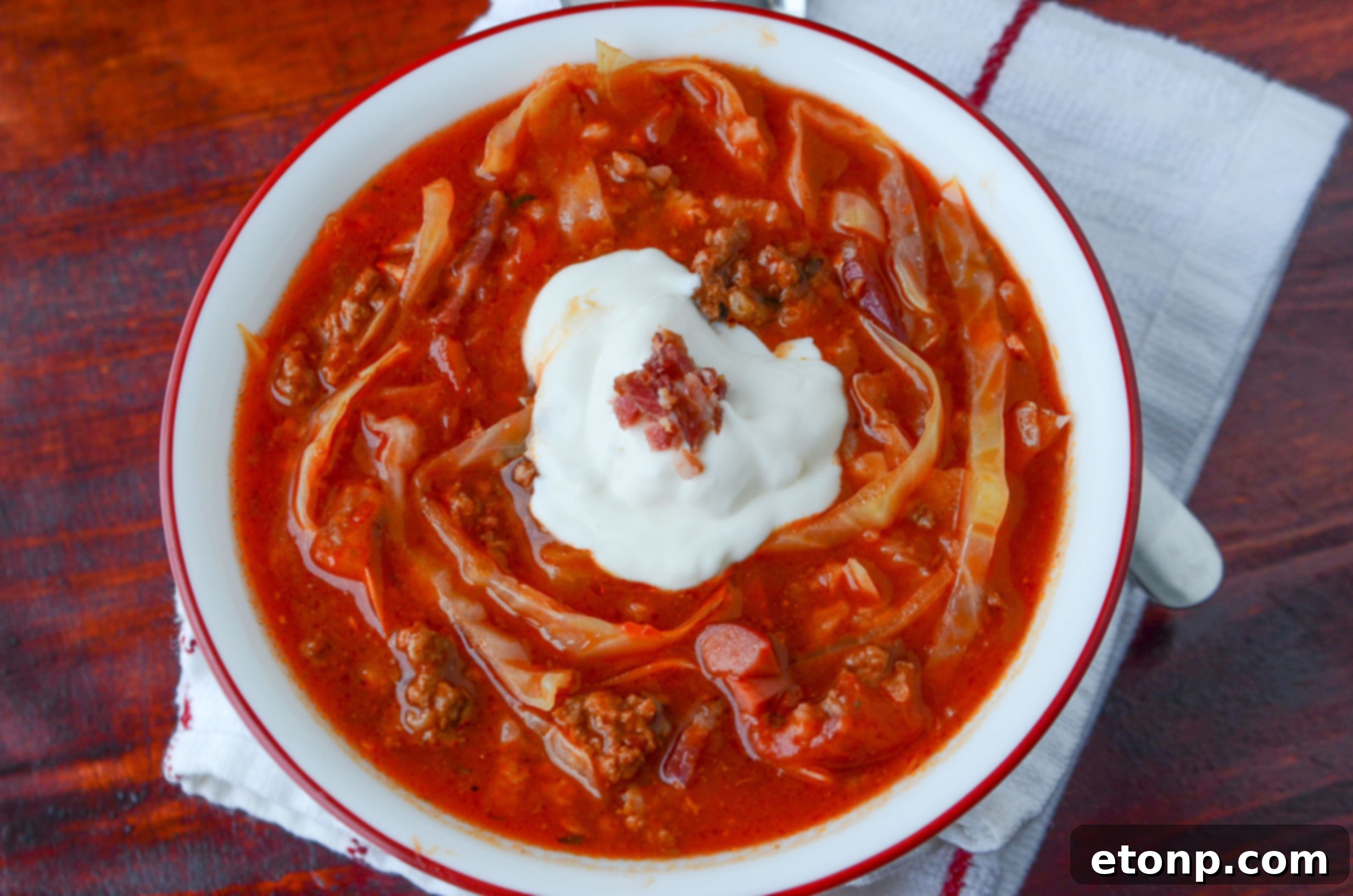 A rustic overhead shot of a slow cooker filled with Crockpot Cabbage Roll Soup, showcasing the ingredients cooking slowly, with a spoon nearby.