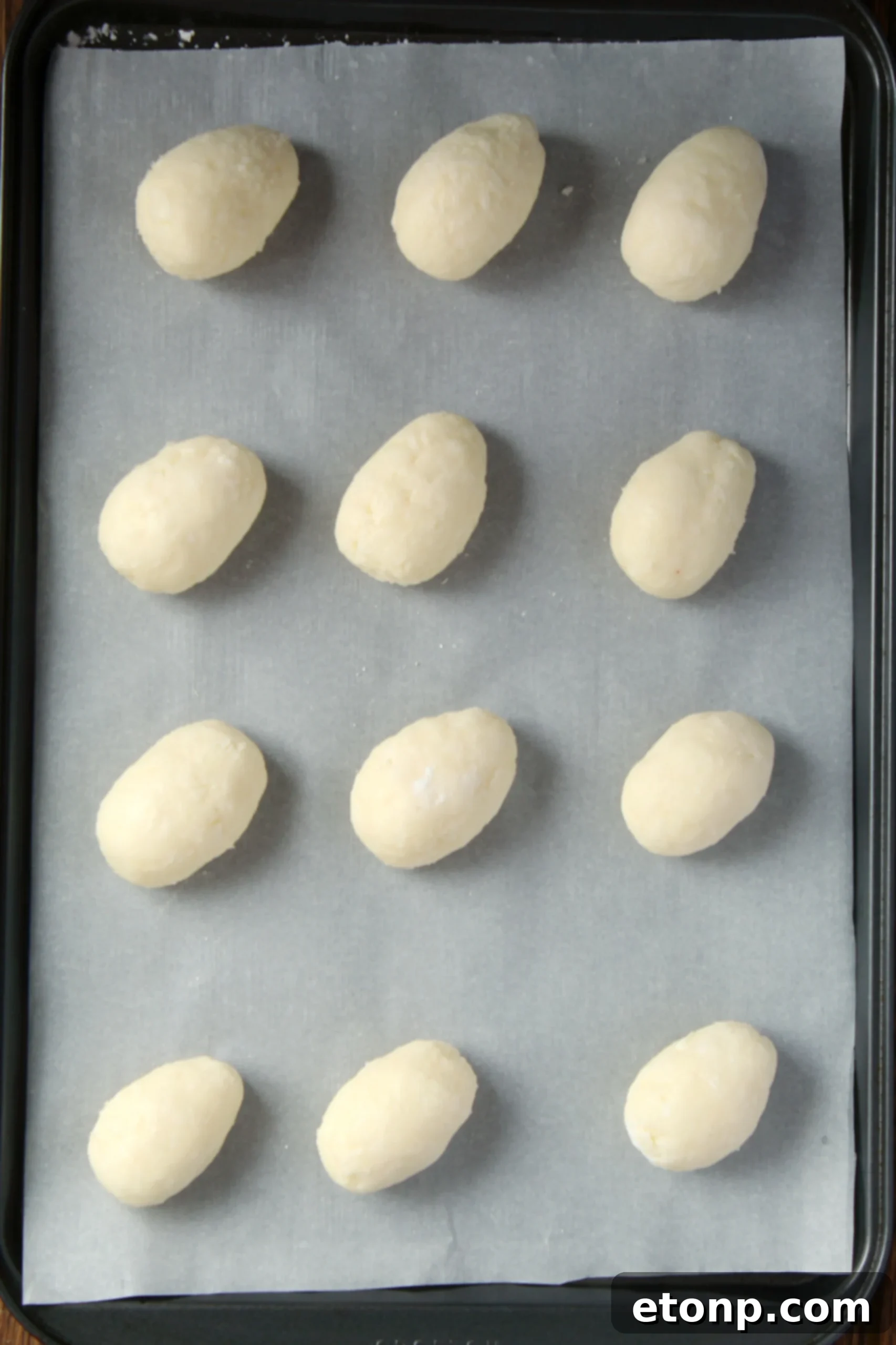 All the essential ingredients for making coconut cream eggs laid out on a clean surface: cream cheese, butter, powdered sugar, shredded coconut, and chocolate chips.