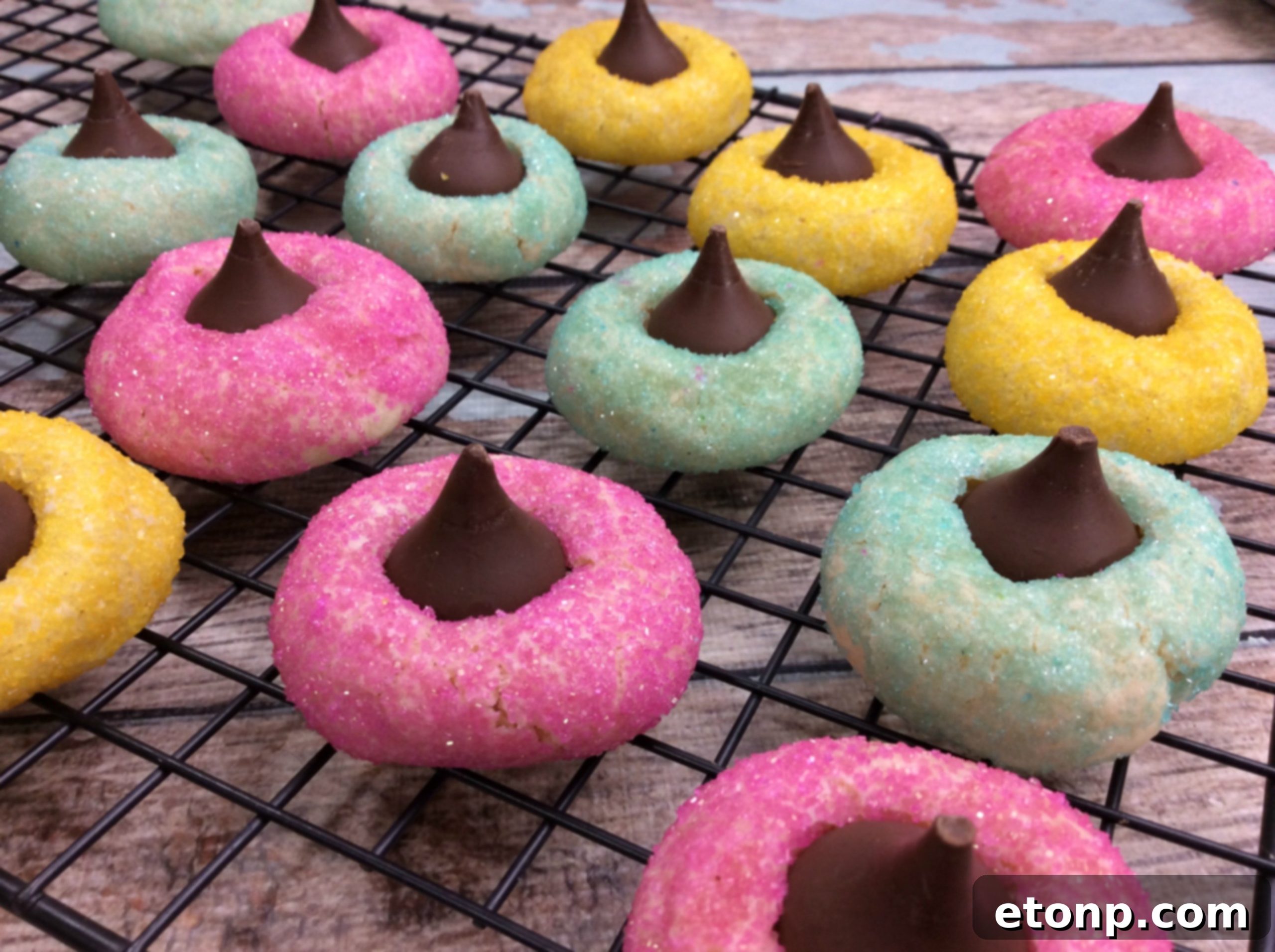 Assortment of vibrant yellow, pink, and green sprinkle-coated cookies arranged neatly on a baking sheet