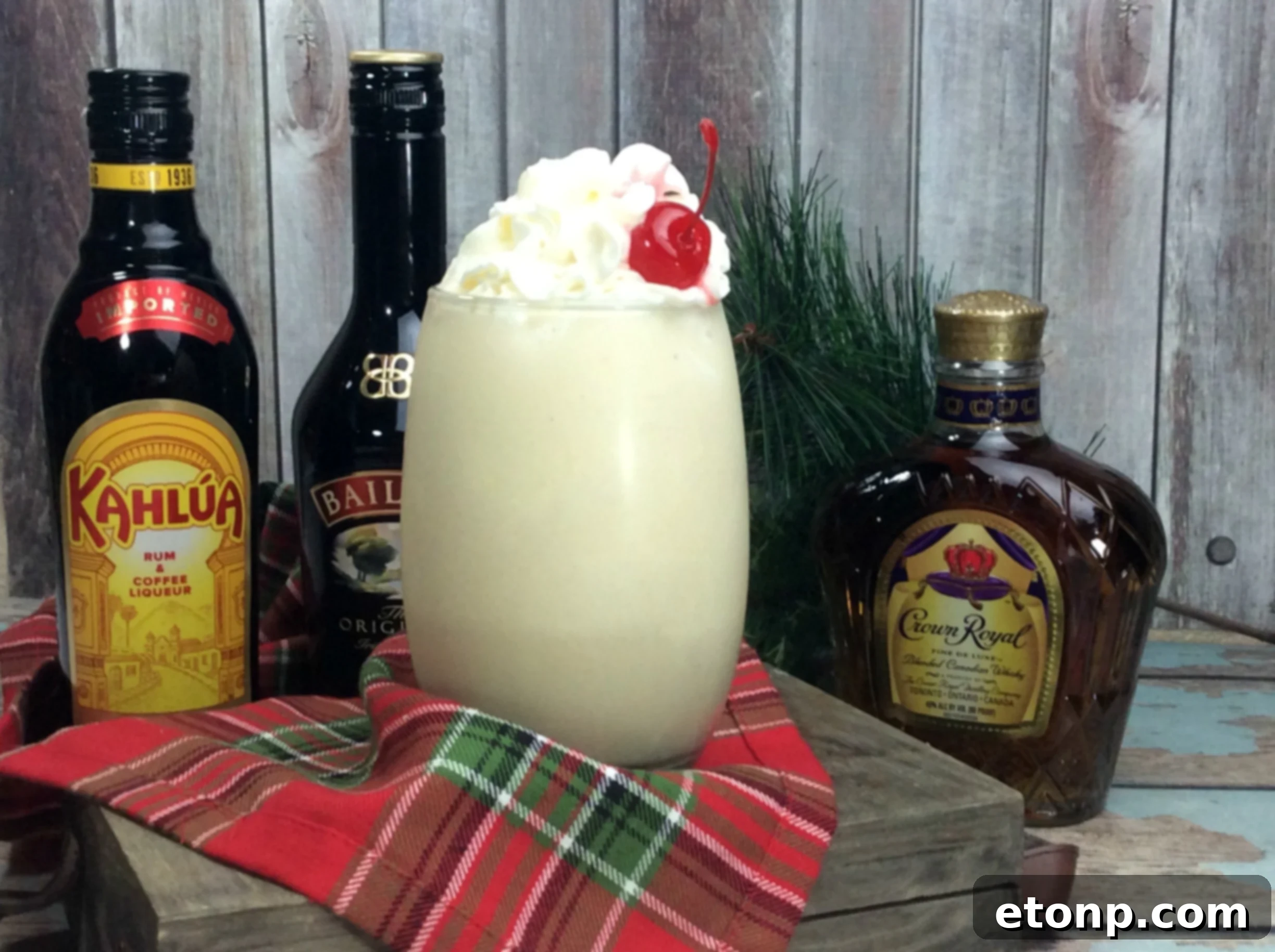 Two glasses of Alaska Duck Fart cocktails, with whipped cream and cherries, on a wooden surface.