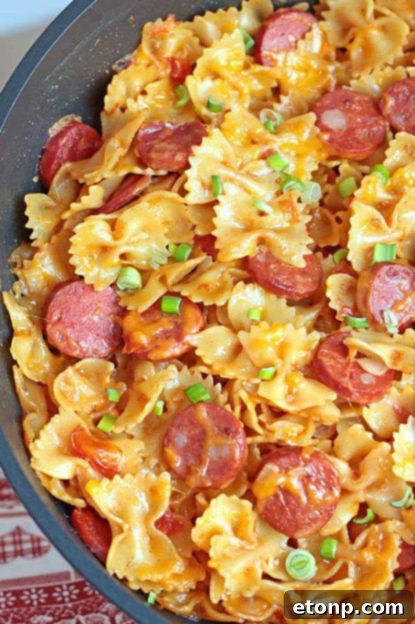 One Pot Kielbasa Pasta with melted cheese and fresh green scallions