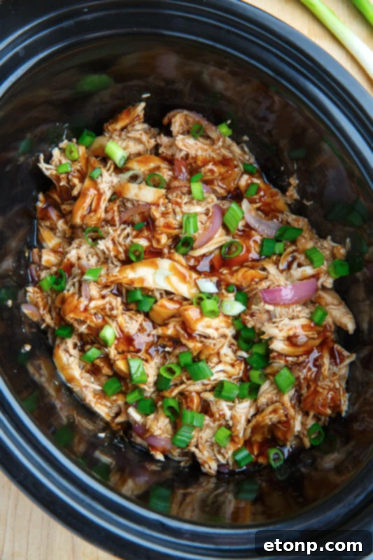 Slow Cooker Honey Garlic Sesame Chicken served over rice, garnished with green onions and sesame seeds