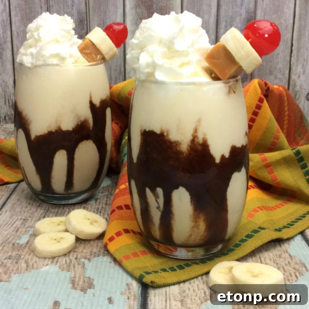 Two Chunky Monkey Cocktails, one garnished with whipped cream and cherry, the other with chocolate and banana slices