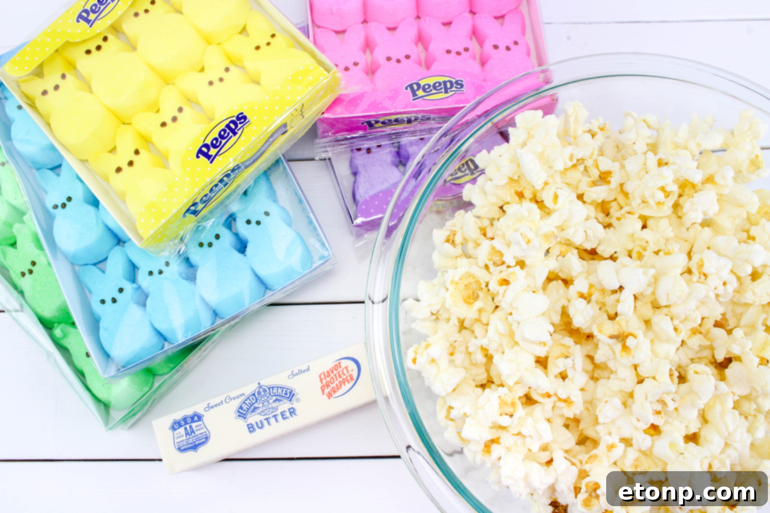 Ingredients for marshmallow popcorn balls, showing colorful PEEPS bunnies and a bowl of popped popcorn.