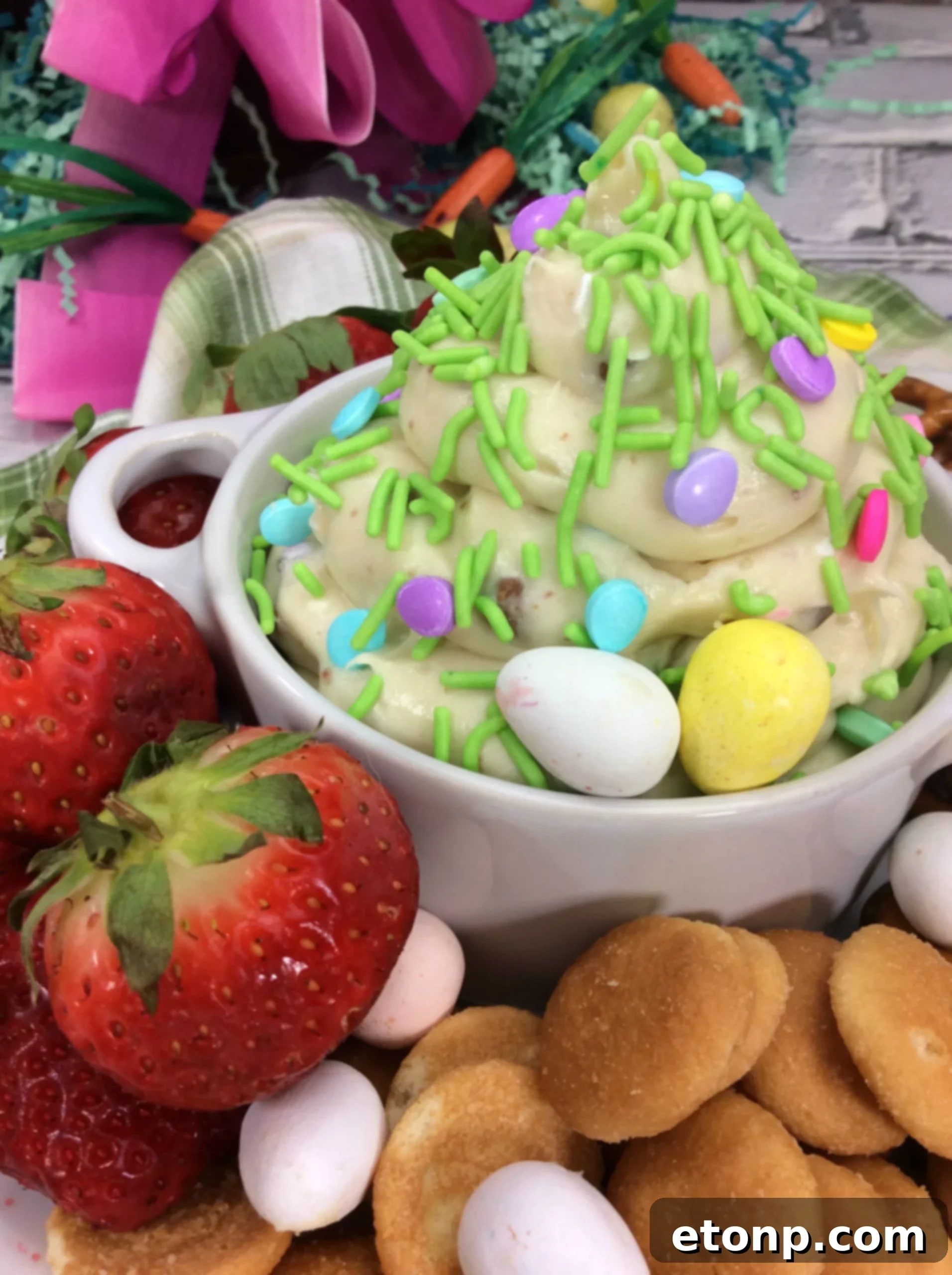 Close-up of creamy Springtime Cheesecake Dip topped with crushed Cadbury Mini Eggs in a white serving bowl, ready to be enjoyed.