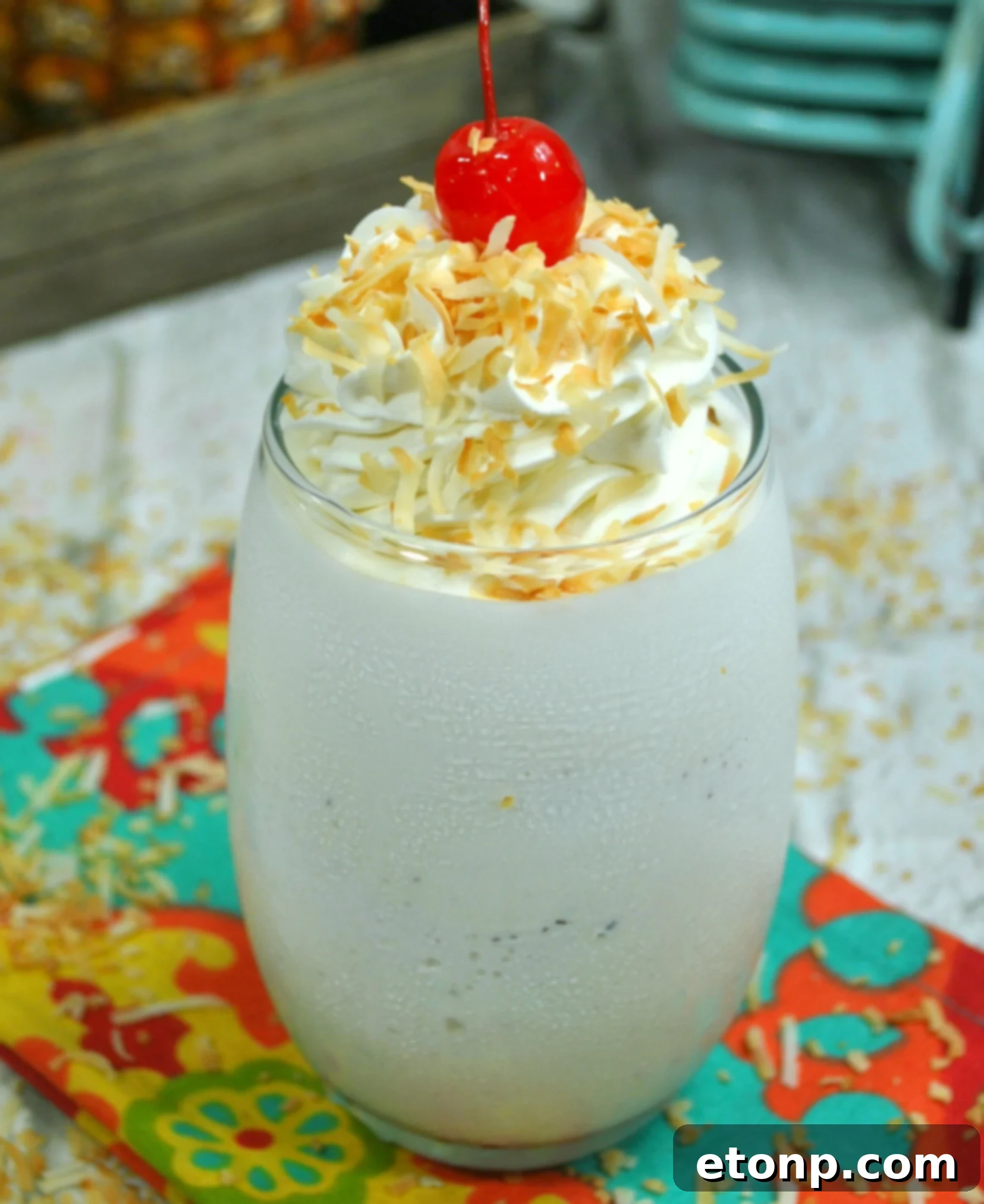 Pina Colada Cocktail 2 Close-up of a refreshing Pina Colada cocktail garnished with a pineapple wedge and cherry, sparkling in a sunlit setting.