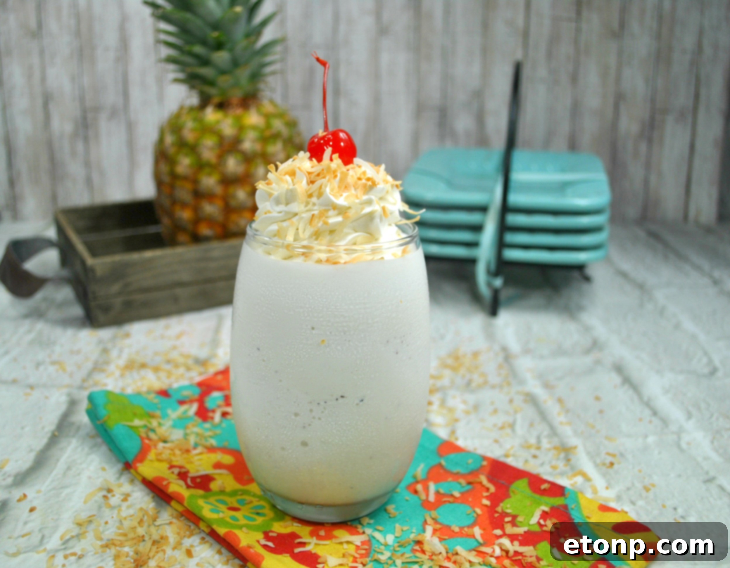 Pina Colada Cocktail 4 A vibrant Pina Colada cocktail in a tall glass, garnished with a red cherry and a straw, against a light background.