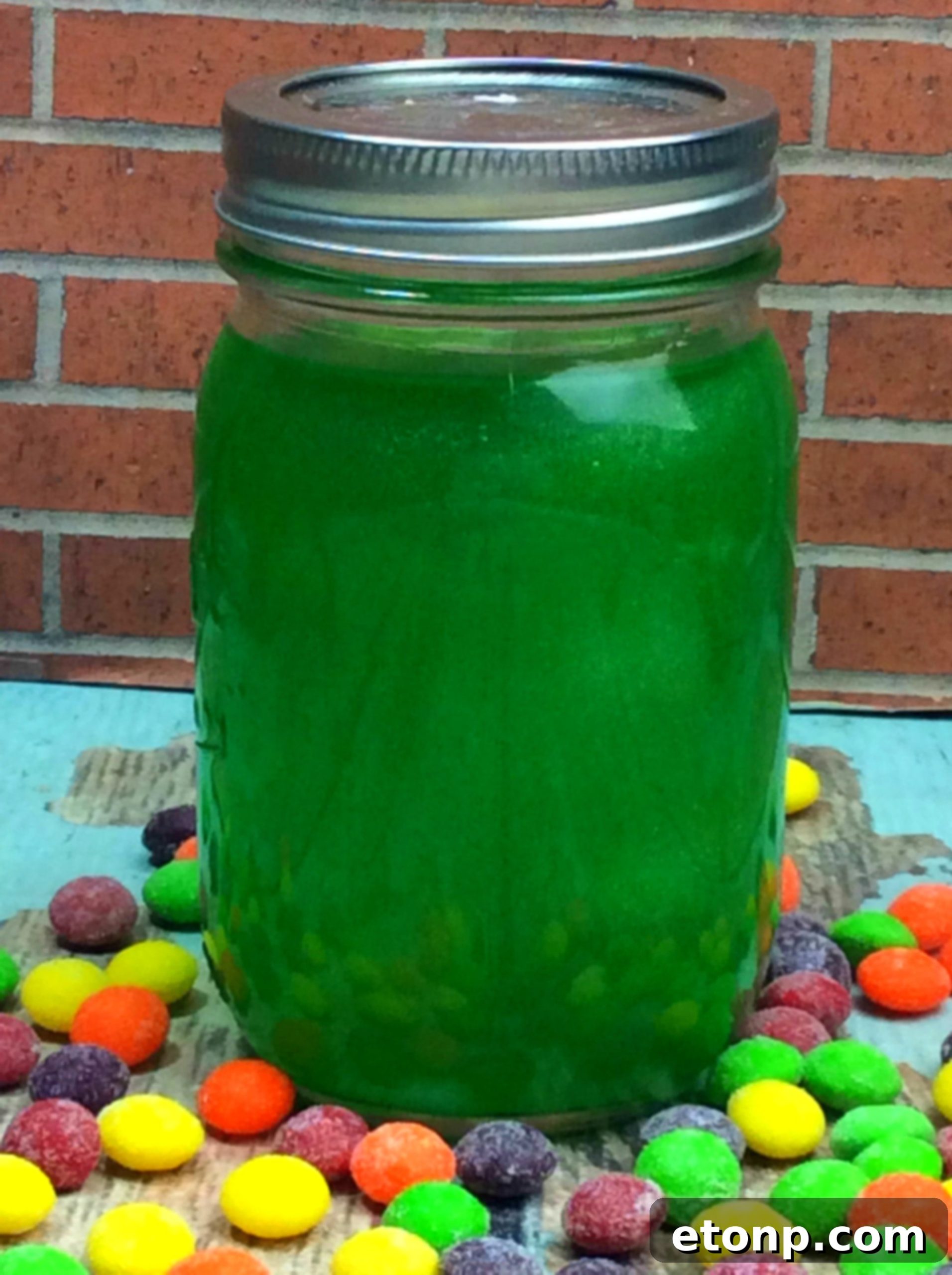 Two mason jars filled with brightly colored Skittles Moonshine, one green and one red.