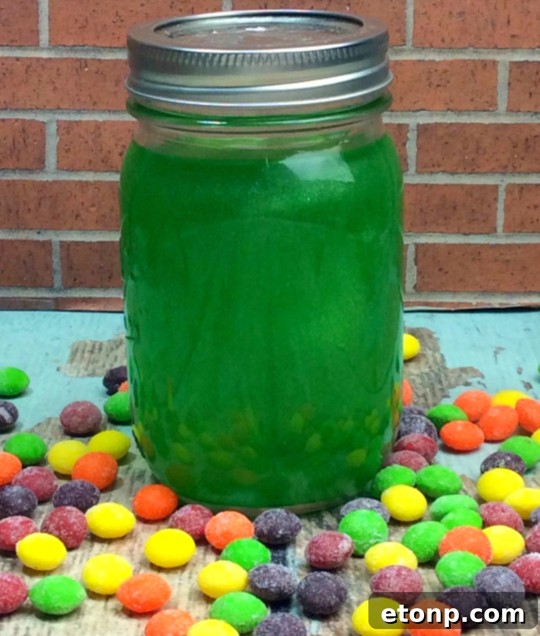 A mason jar containing green Skittles and Everclear, midway through the infusion process.