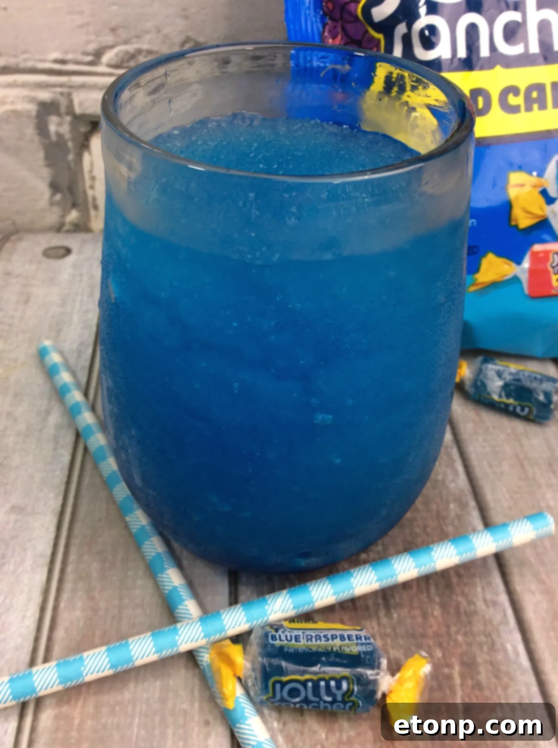 Several Blue Raspberry Jolly Rancher candies next to a bottle of vodka, hinting at the infusion process.