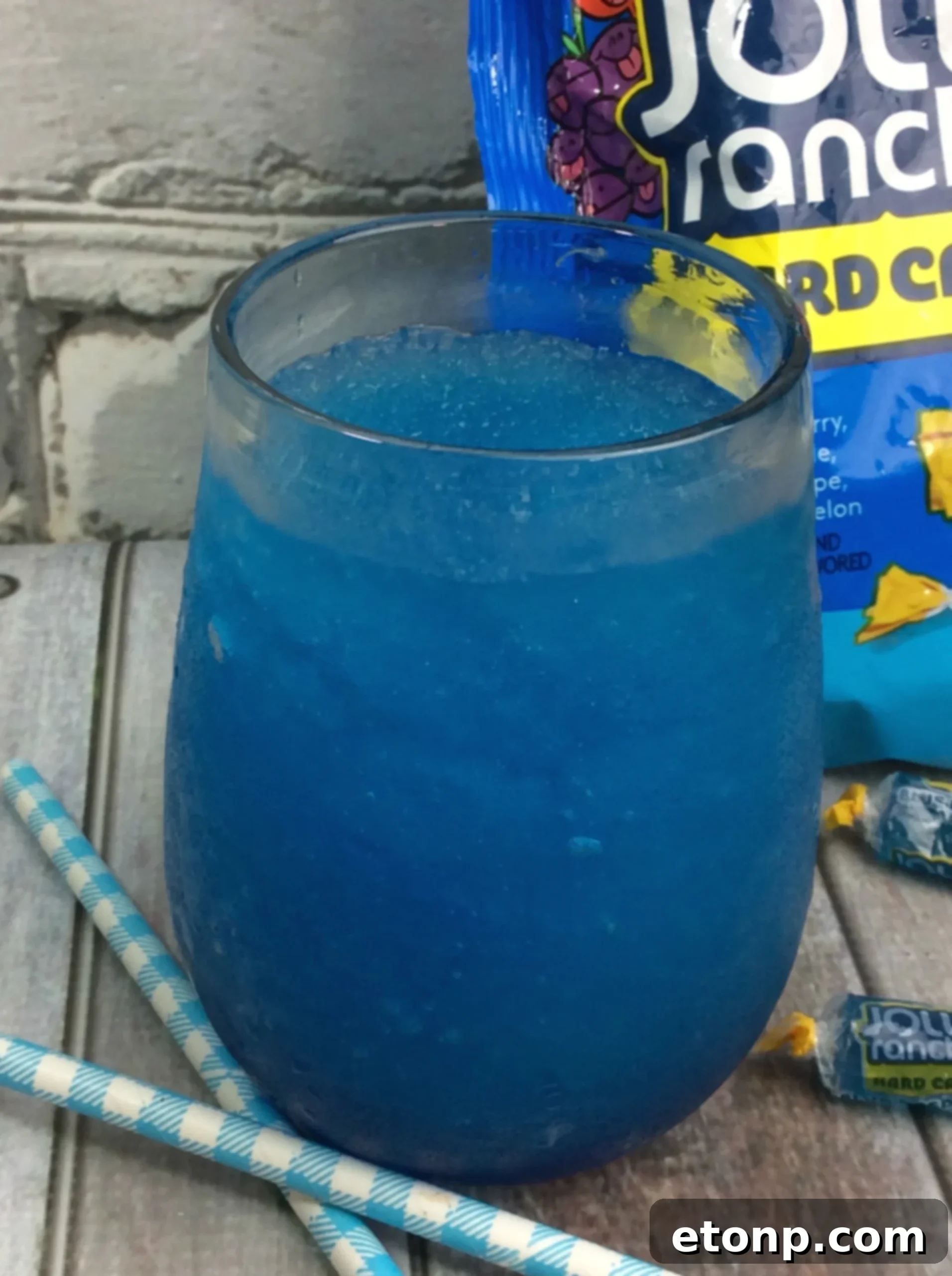Close-up of a hand pouring Blue Raspberry Jolly Rancher infused vodka into a blender.