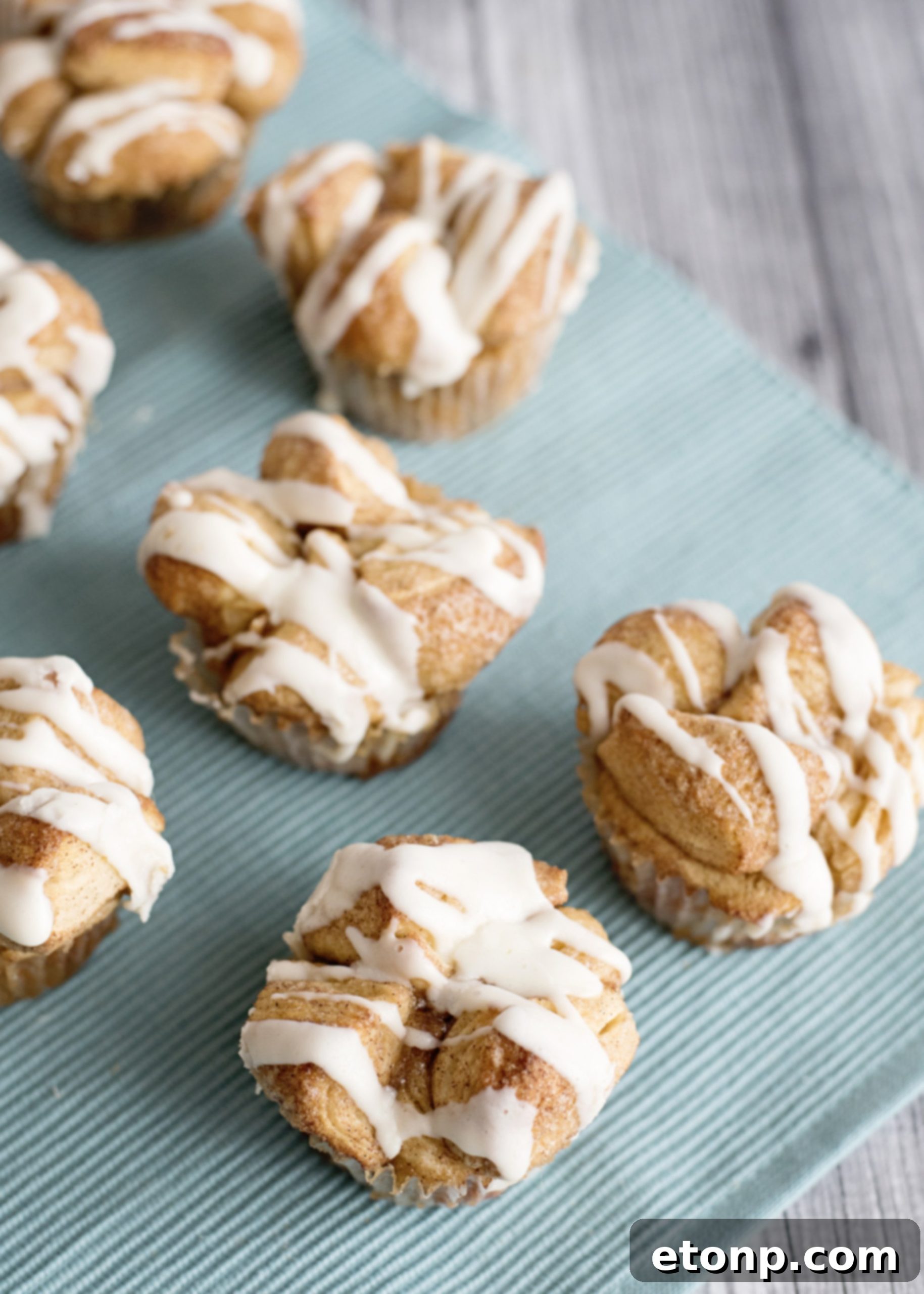 Snickerdoodle Monkey Bread Muffins, freshly drizzled with cream cheese frosting, ready to be served.