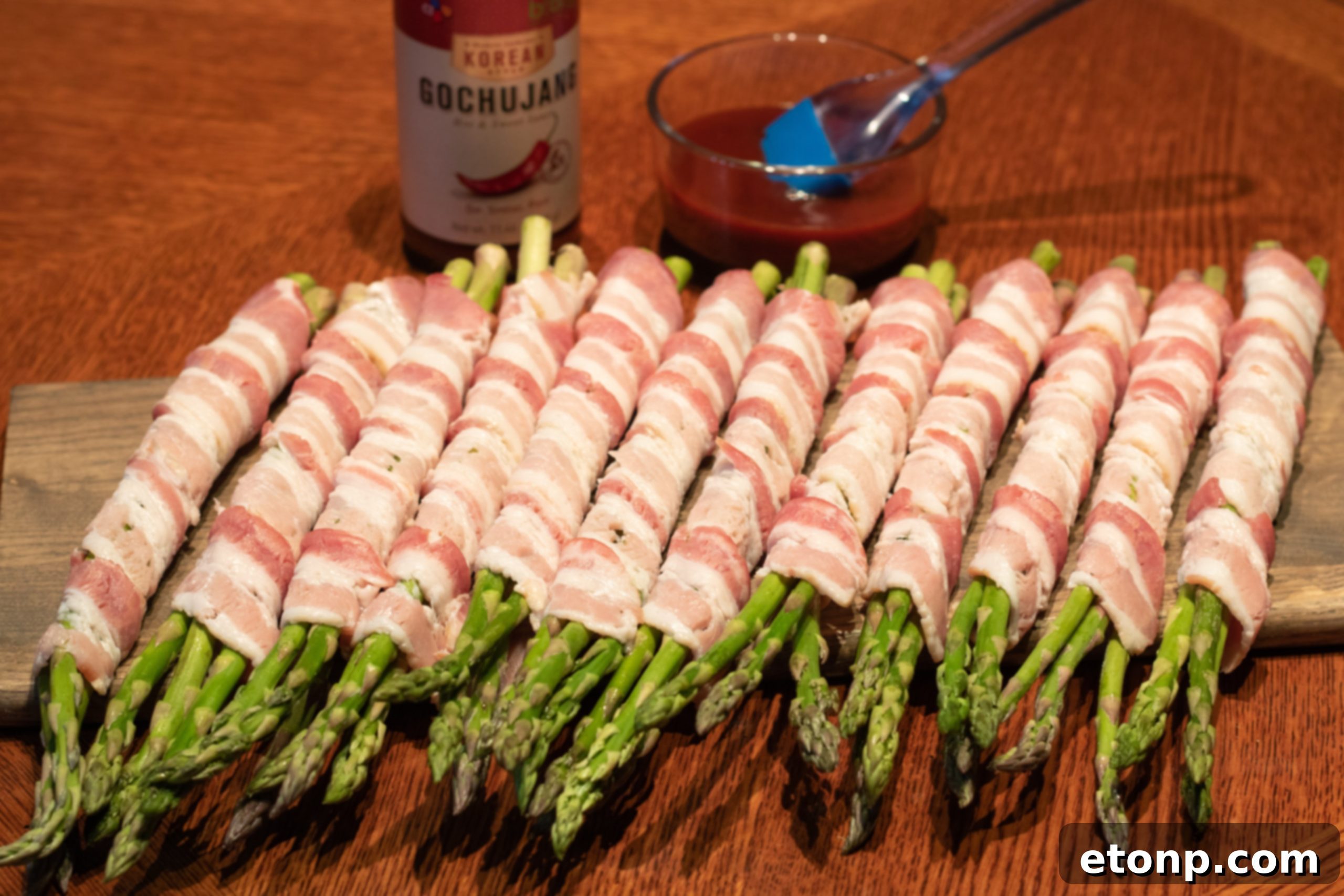 Three bundles of bacon wrapped asparagus on a wooden board