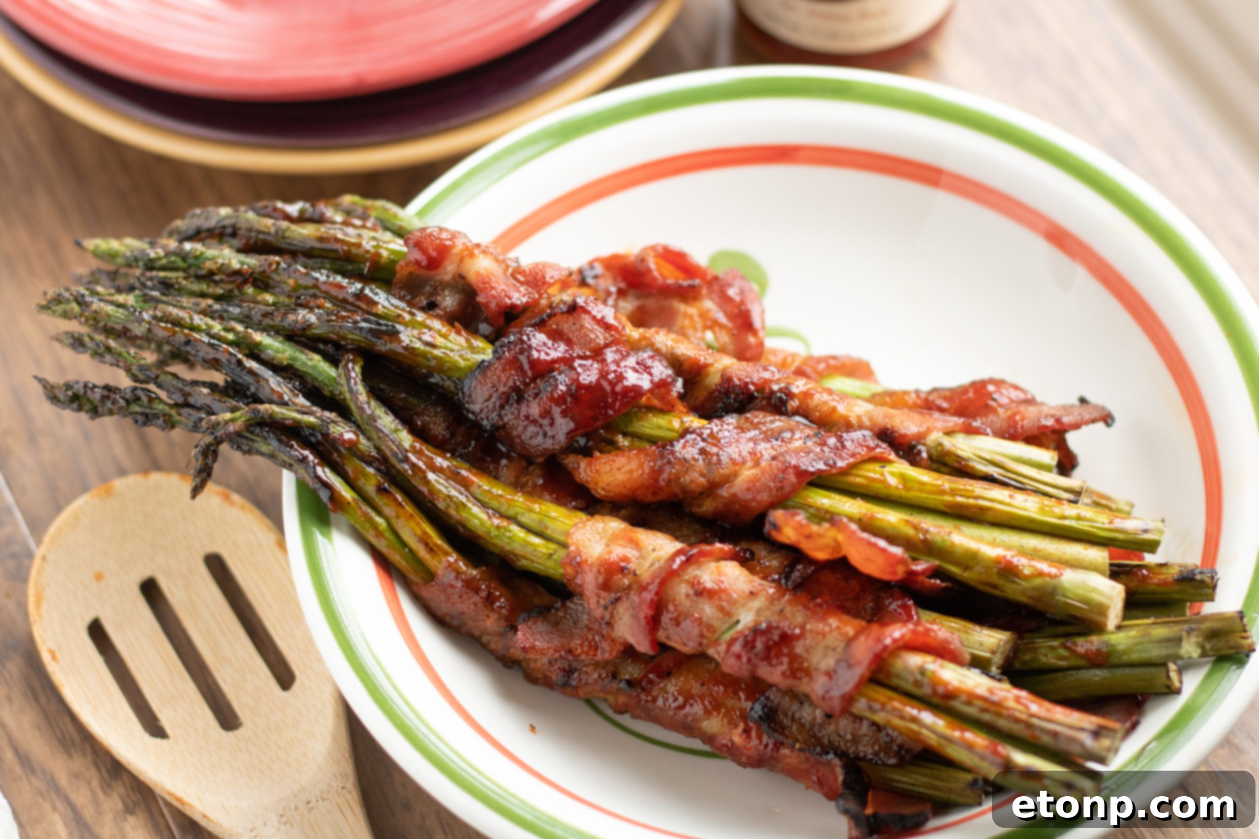 Bundles of bacon wrapped asparagus on a baking sheet before cooking