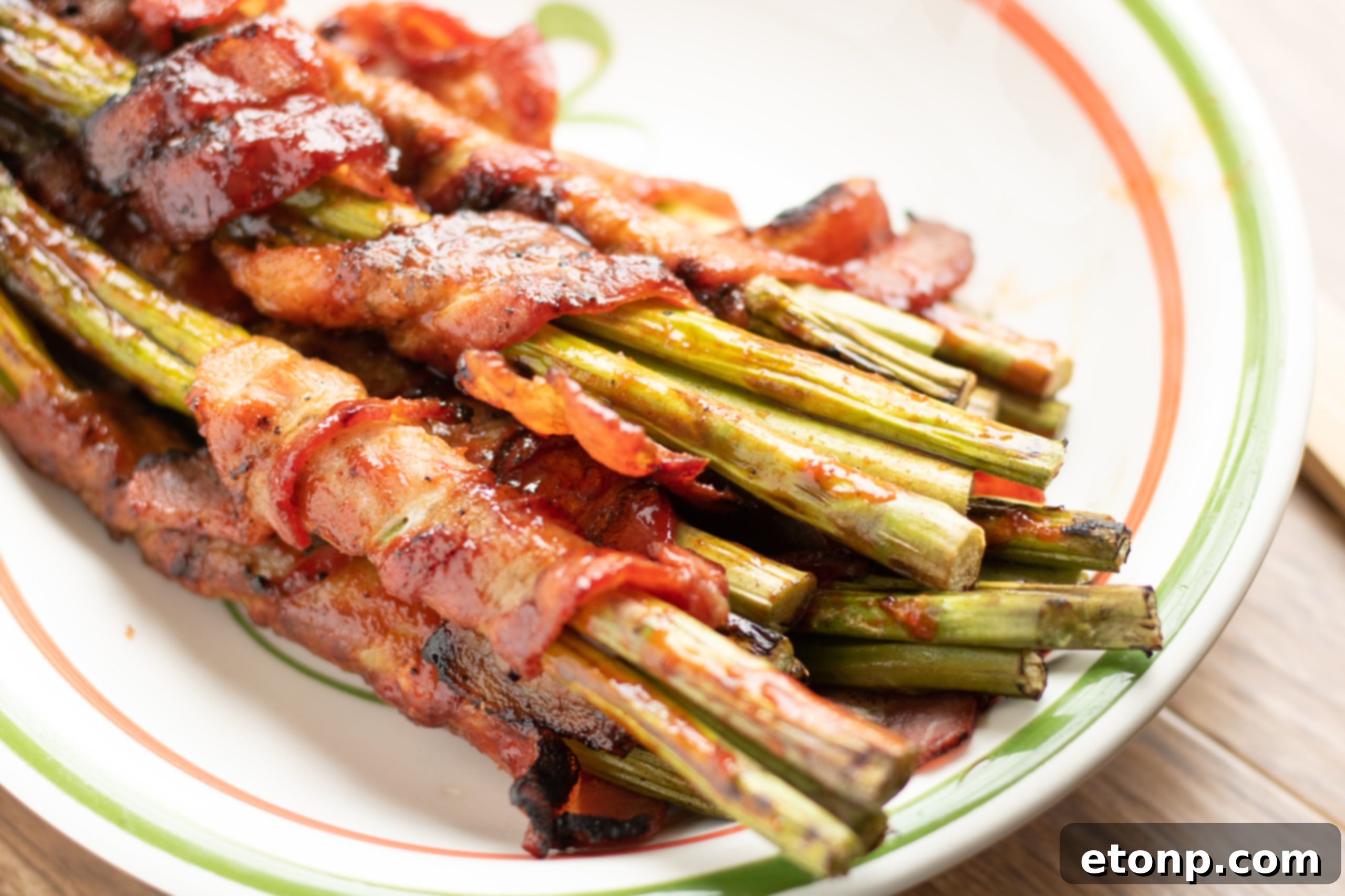 Cooked bacon wrapped asparagus bundles arranged on a white serving dish