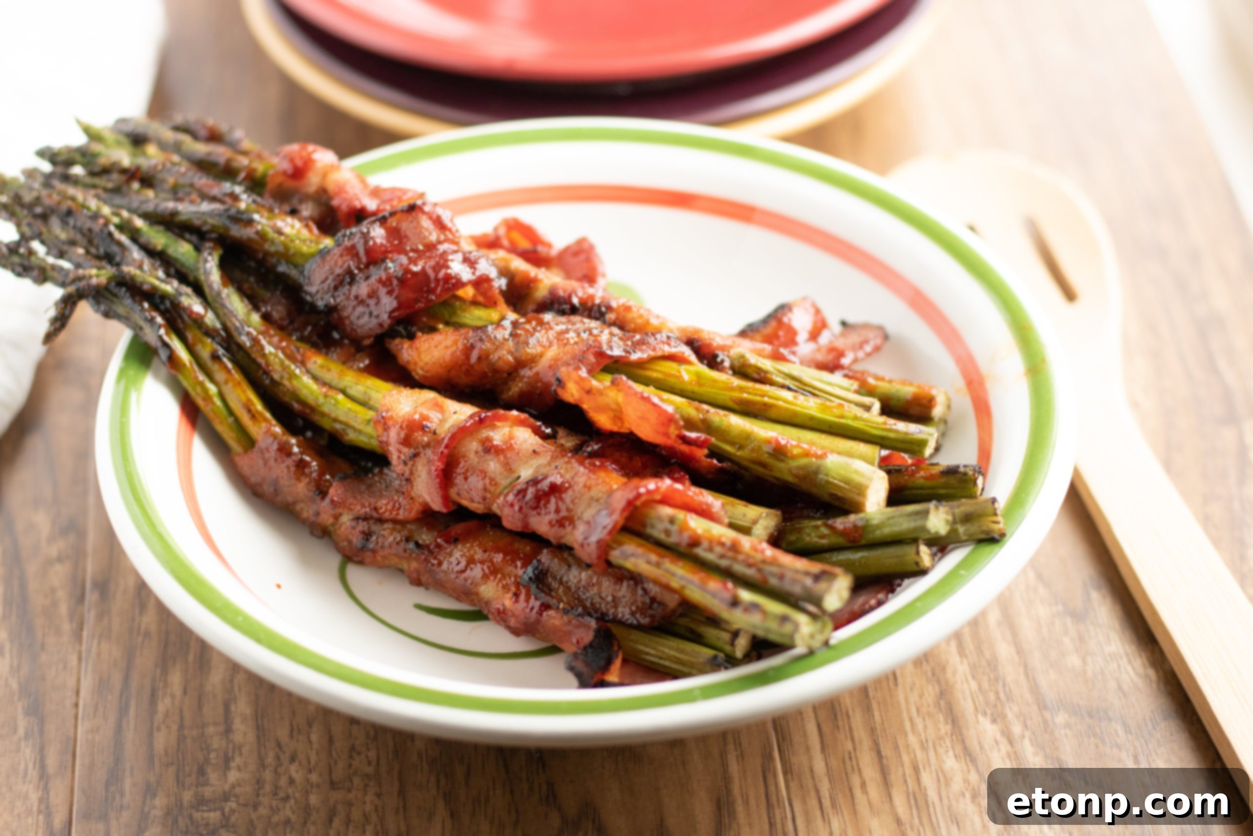 Cooked bacon wrapped asparagus bundles with a serving utensil