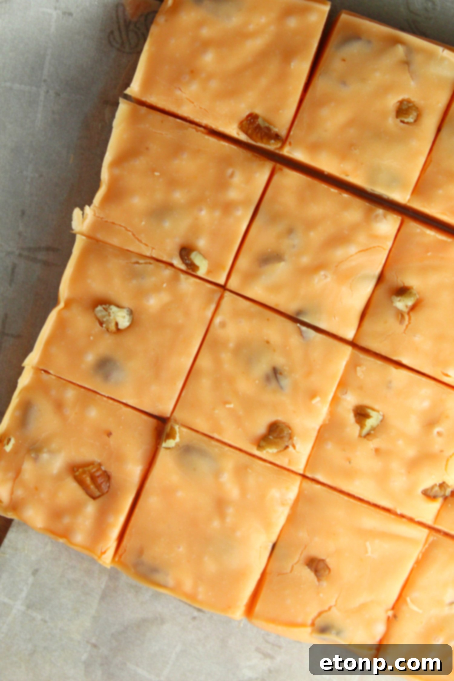 Stack of freshly made pumpkin fudge squares on a wooden board