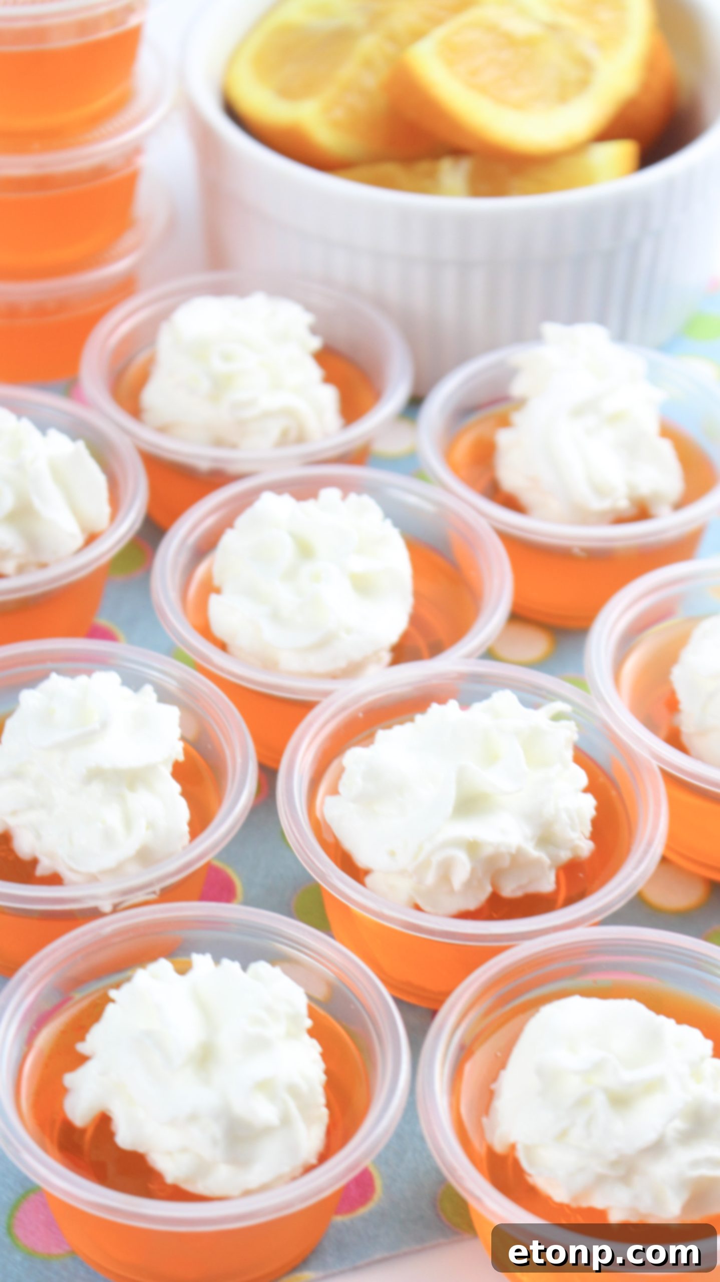 Arrangement of several Orange Creamsicle Jello Shots in plastic cups, showcasing their readiness for serving.