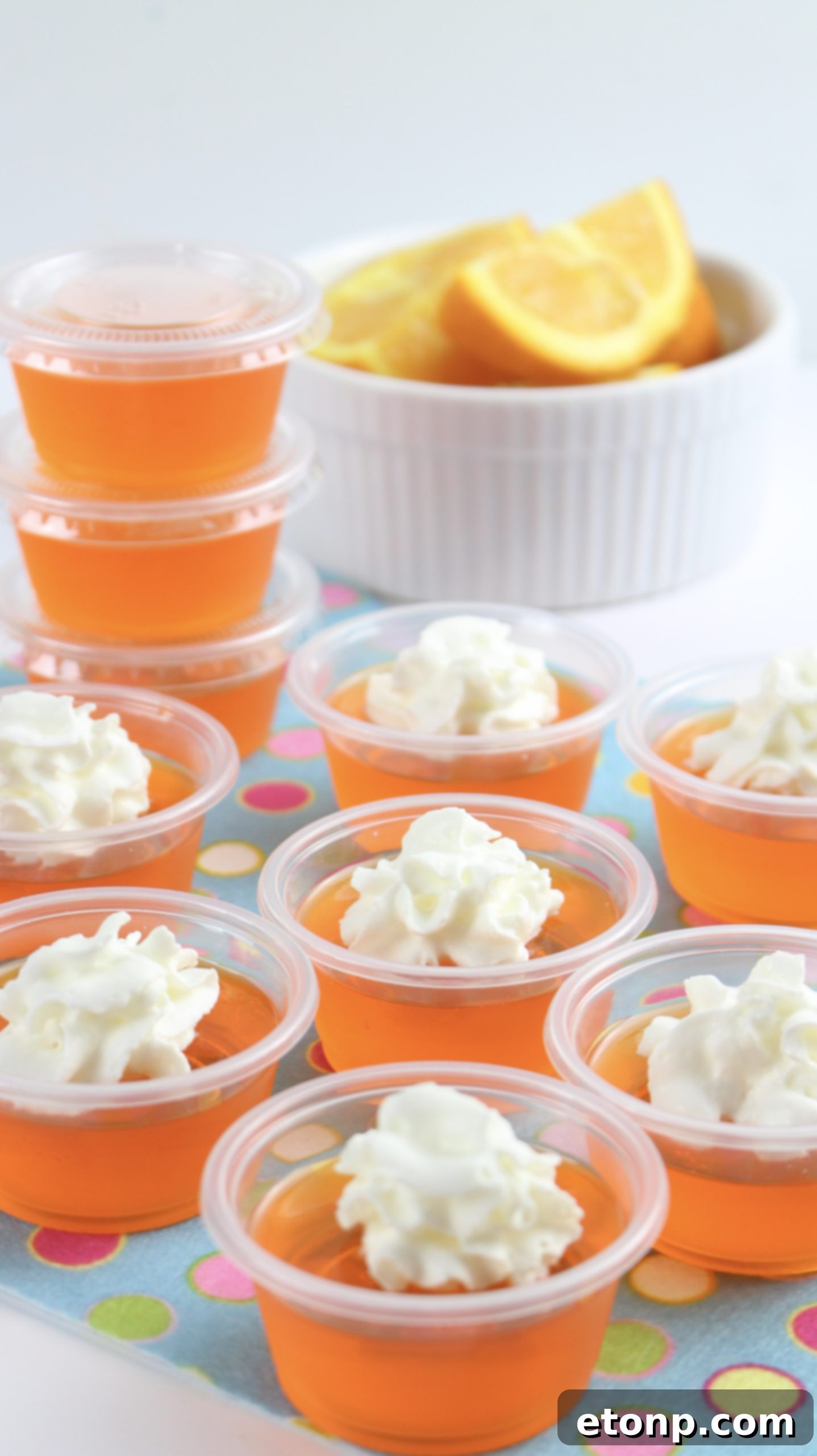 Various angles of Orange Creamsicle Jello Shots with whipped cream, demonstrating their appealing presentation and party-readiness.