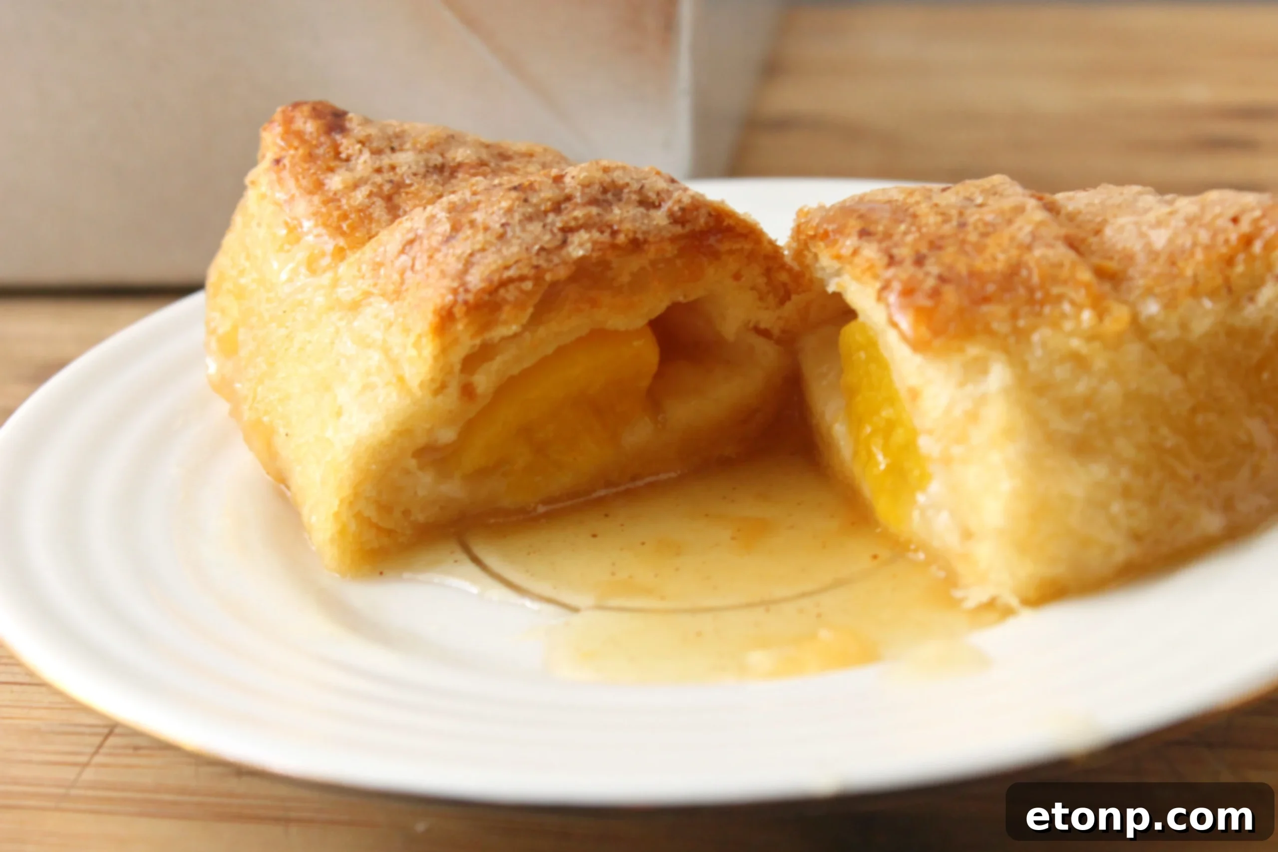 Close-up of baked peach dumplings in a casserole dish, showing the flaky crescent roll crust and glistening syrup.