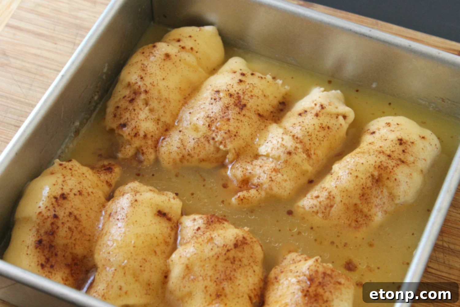 Another perspective of the assembled peach dumplings, perfectly aligned in the baking pan before the sauce is added.