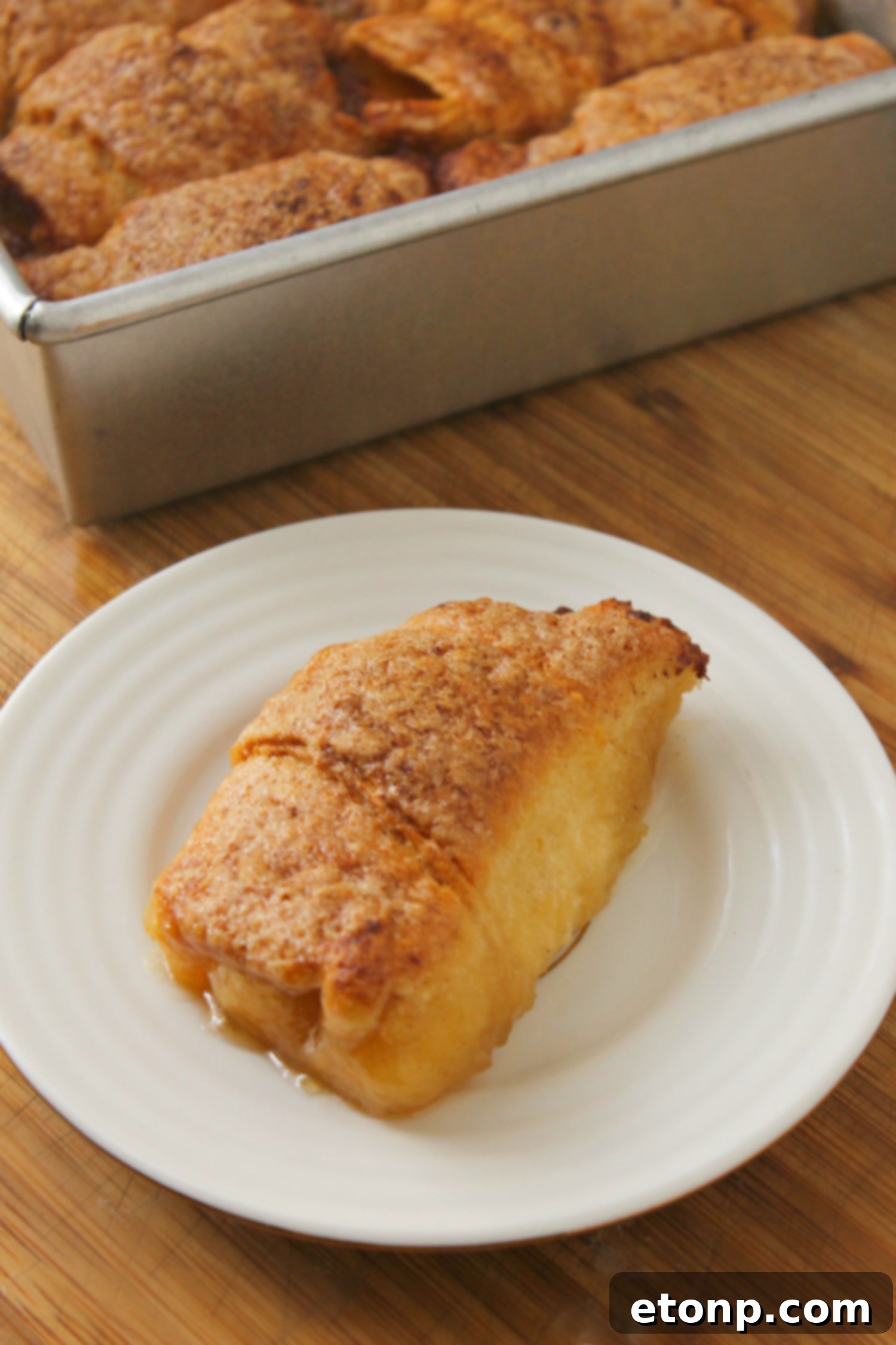 A beautifully presented peach dumpling on a plate, showcasing its golden crust and juicy peach filling, ready to be enjoyed.