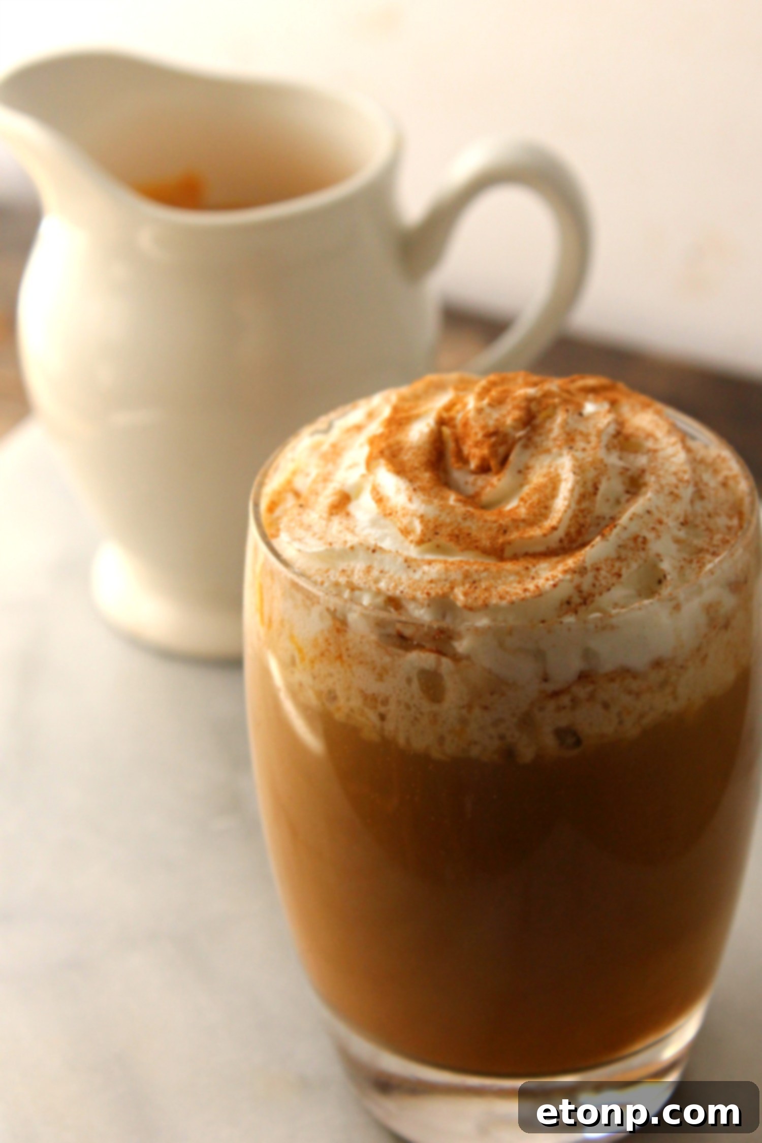 A freshly brewed cup of coffee with a swirl of homemade pumpkin spice creamer, garnished with cinnamon stick and a sprinkle of spice, evoking cozy autumn mornings.