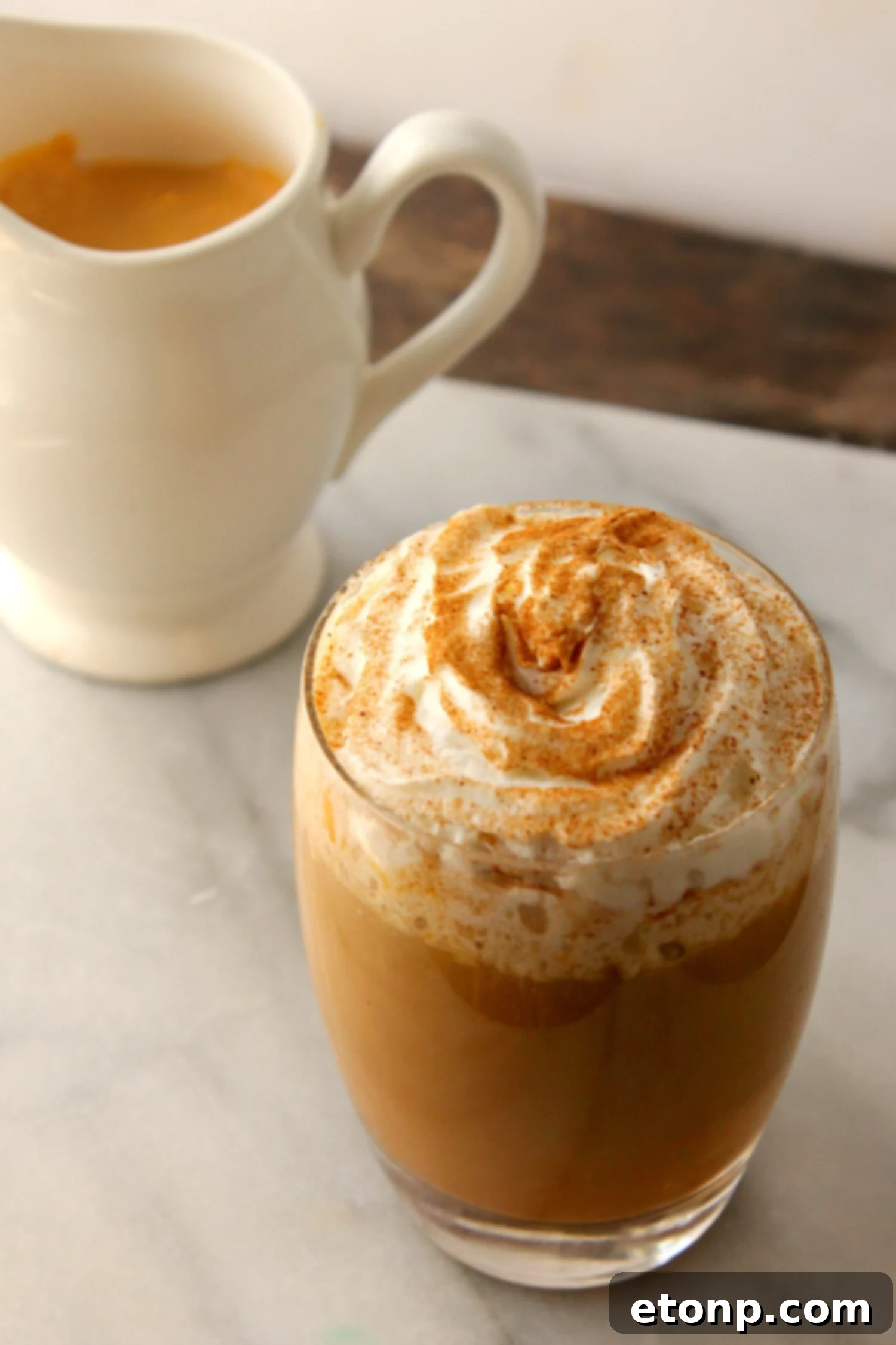 Ingredients for homemade pumpkin spice creamer laid out on a rustic wooden surface, including whole milk, pumpkin puree, maple syrup, pumpkin pie spice, and vanilla extract.