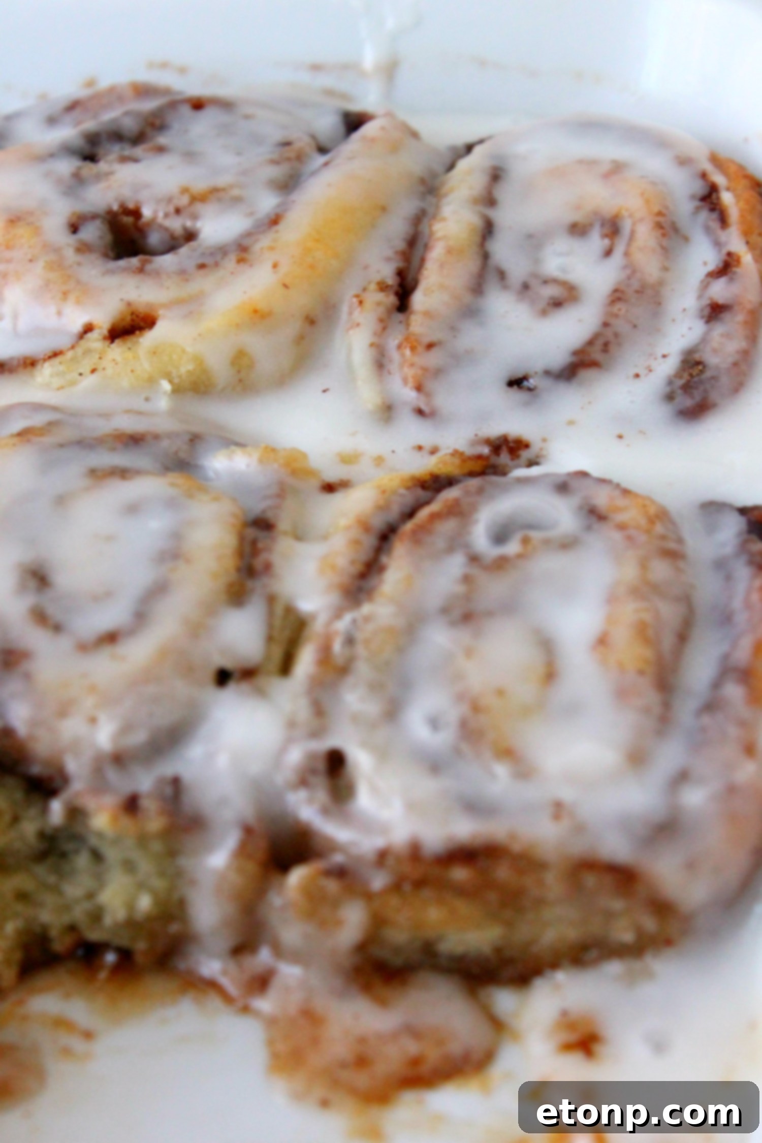 45 Minute Cinnamon Roll Magic 5 Several glistening cinnamon rolls cooling on a wire rack, covered in sweet icing.