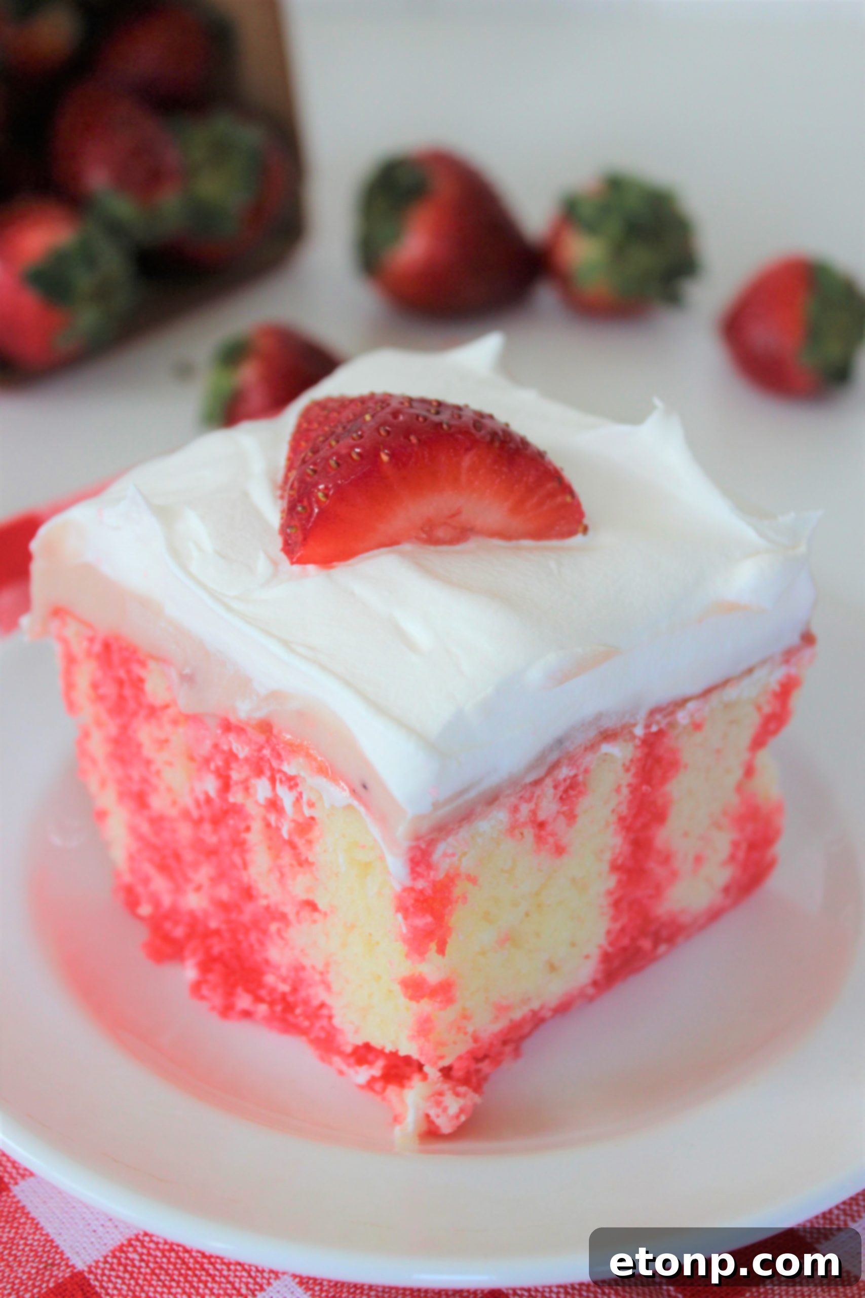 Irresistible Strawberry Cheesecake Poke Cake 5 Close-up of Strawberry Cheesecake Poke Cake with whipped cream and fresh strawberries