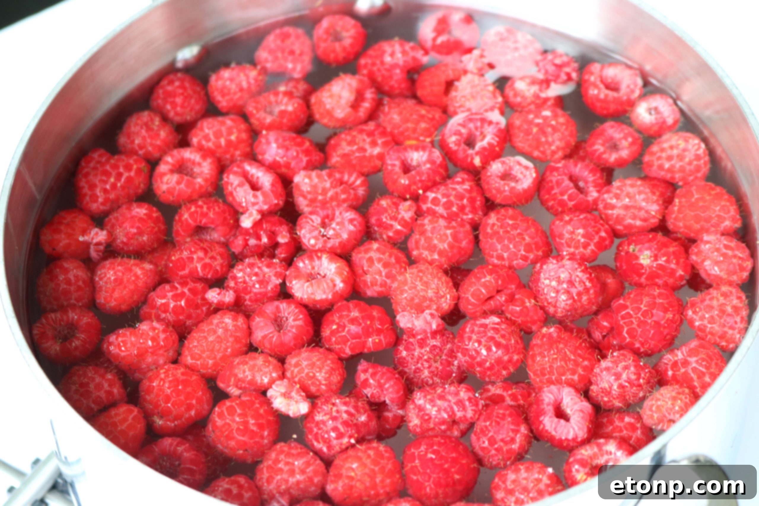 Close-up of Raspberry Sweet Tea in a mason jar with fresh raspberries and ice
