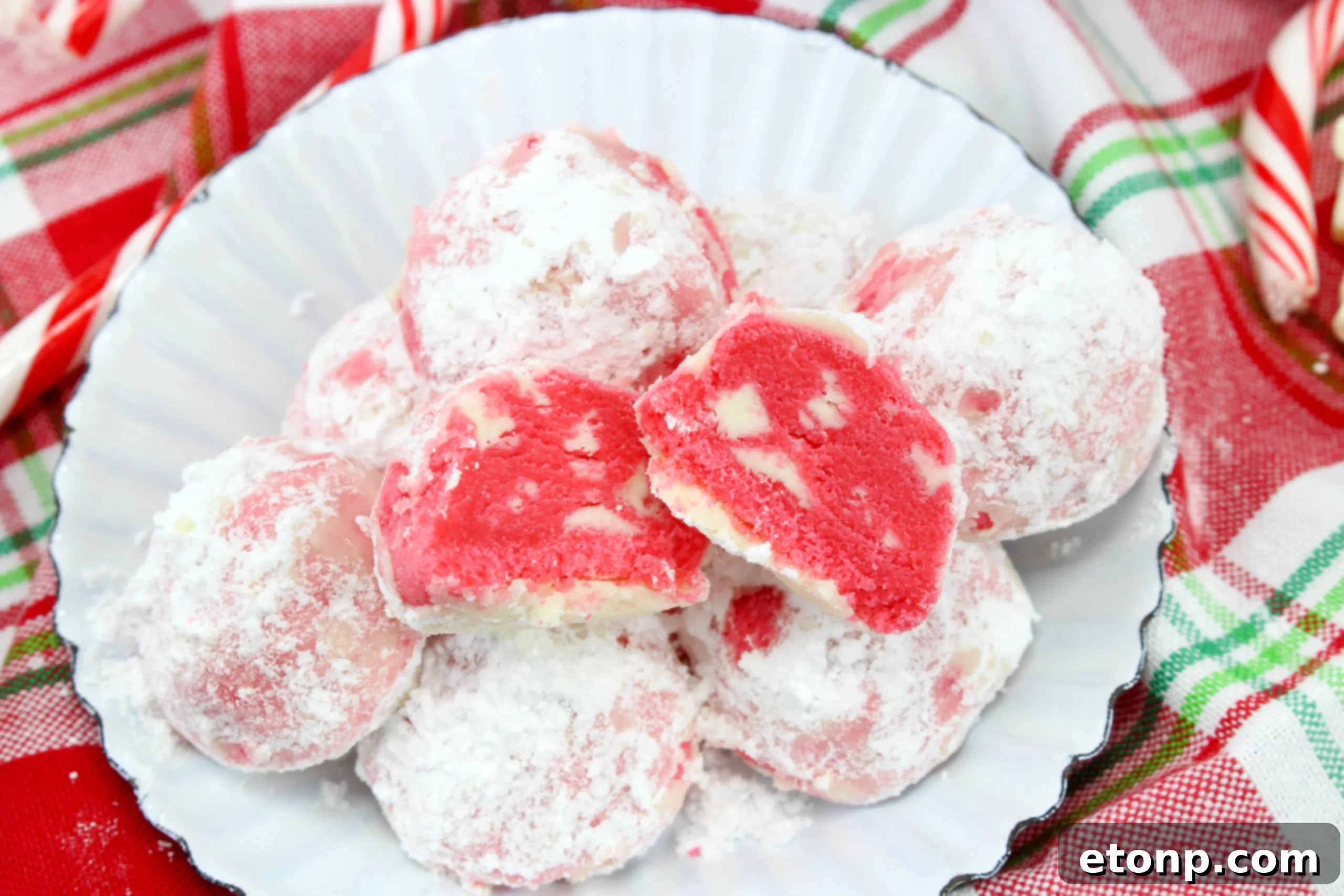 Close-up of a snowball cookie, revealing its crumbly, shortbread texture and a peek of peppermint chocolate inside.