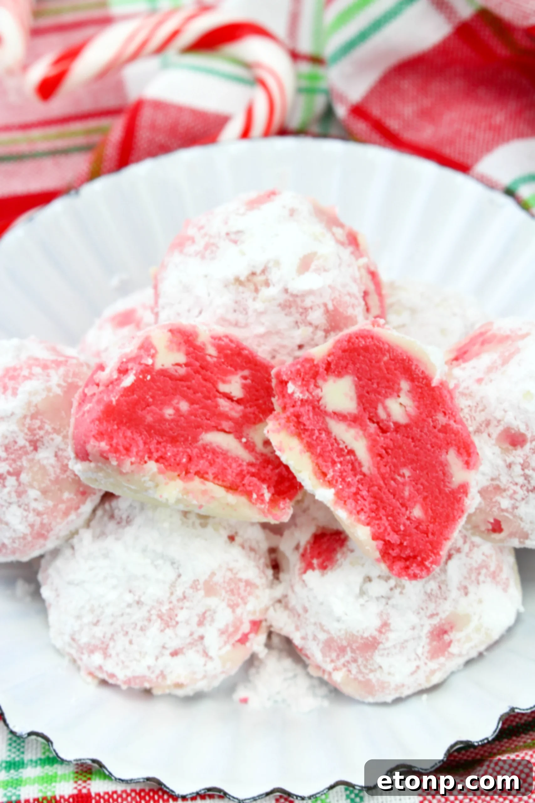Freshly baked peppermint snowball cookies cooling on a wire rack before being coated in powdered sugar.