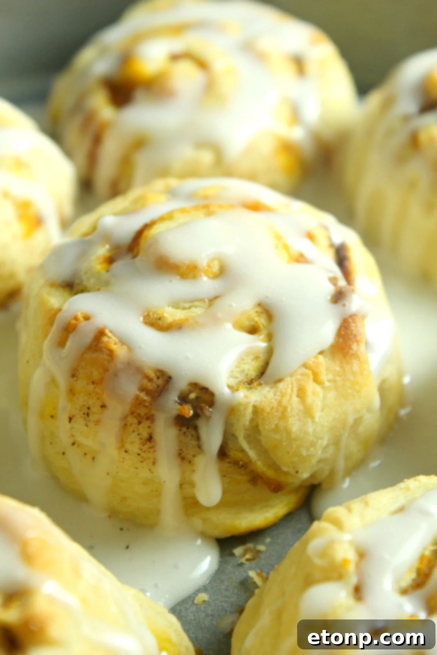 Close-up of freshly baked pumpkin cinnamon rolls, golden brown and swirled with pumpkin spice filling, cooling on a wire rack.