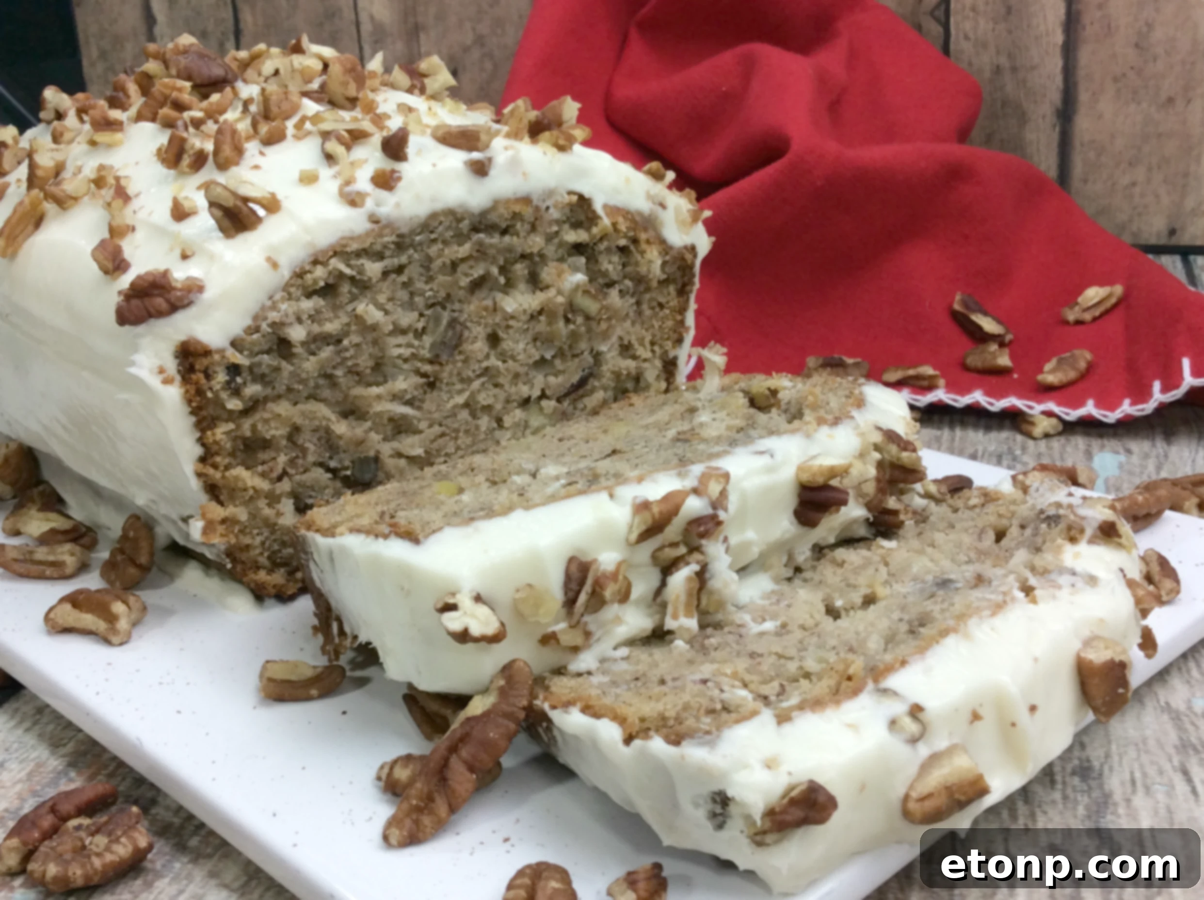A perfectly frosted Southern Hummingbird Bread loaf, topped with chopped pecans, ready to be sliced and served.