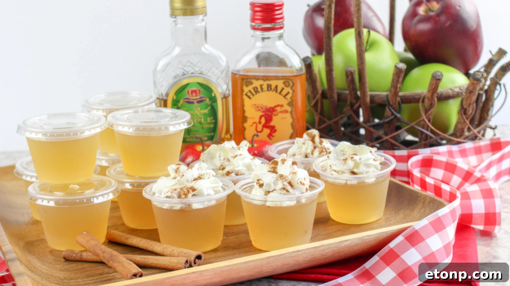 Spiced Apple Pie Shooters 5 Several neatly arranged Apple Pie Jello Shots in small plastic cups, showcasing their amber hue.